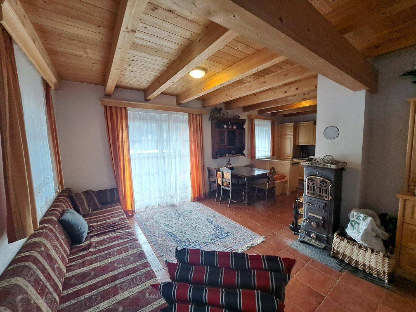 Gemütlicher Wohn-Essbereich mit Holzbalkendecke, Kaminofen und rustikalen Möbeln.