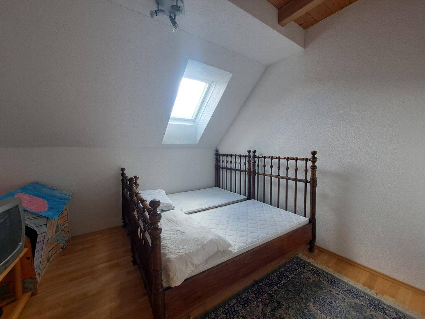 Helles Schlafzimmer im Dachgeschoss mit Einzelbetten, Holzboden und Dachfenster.
