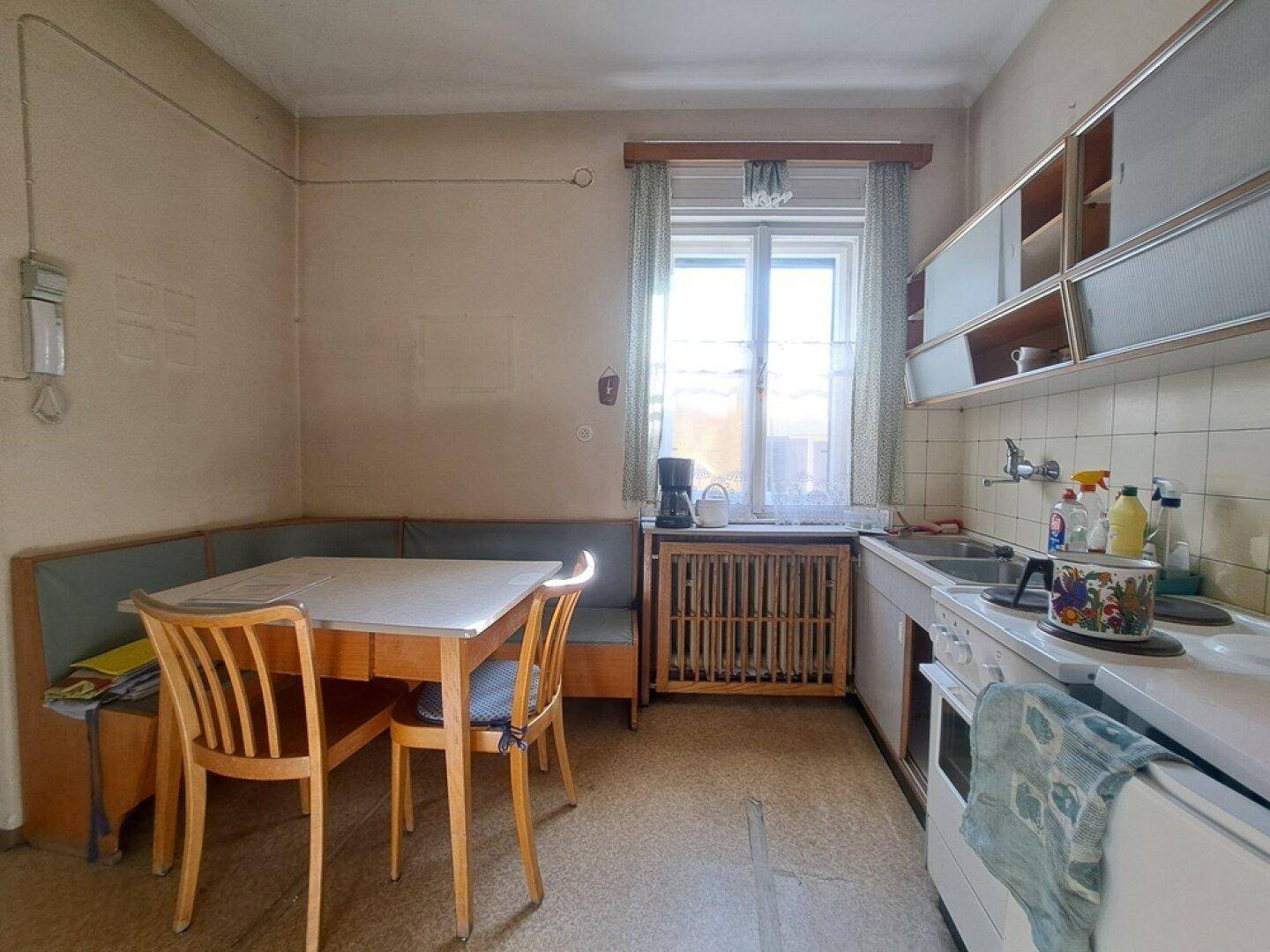 Funktionale Küche mit einer gemütlichen Essecke, Spüle und einem Herd unter dem Fenster.