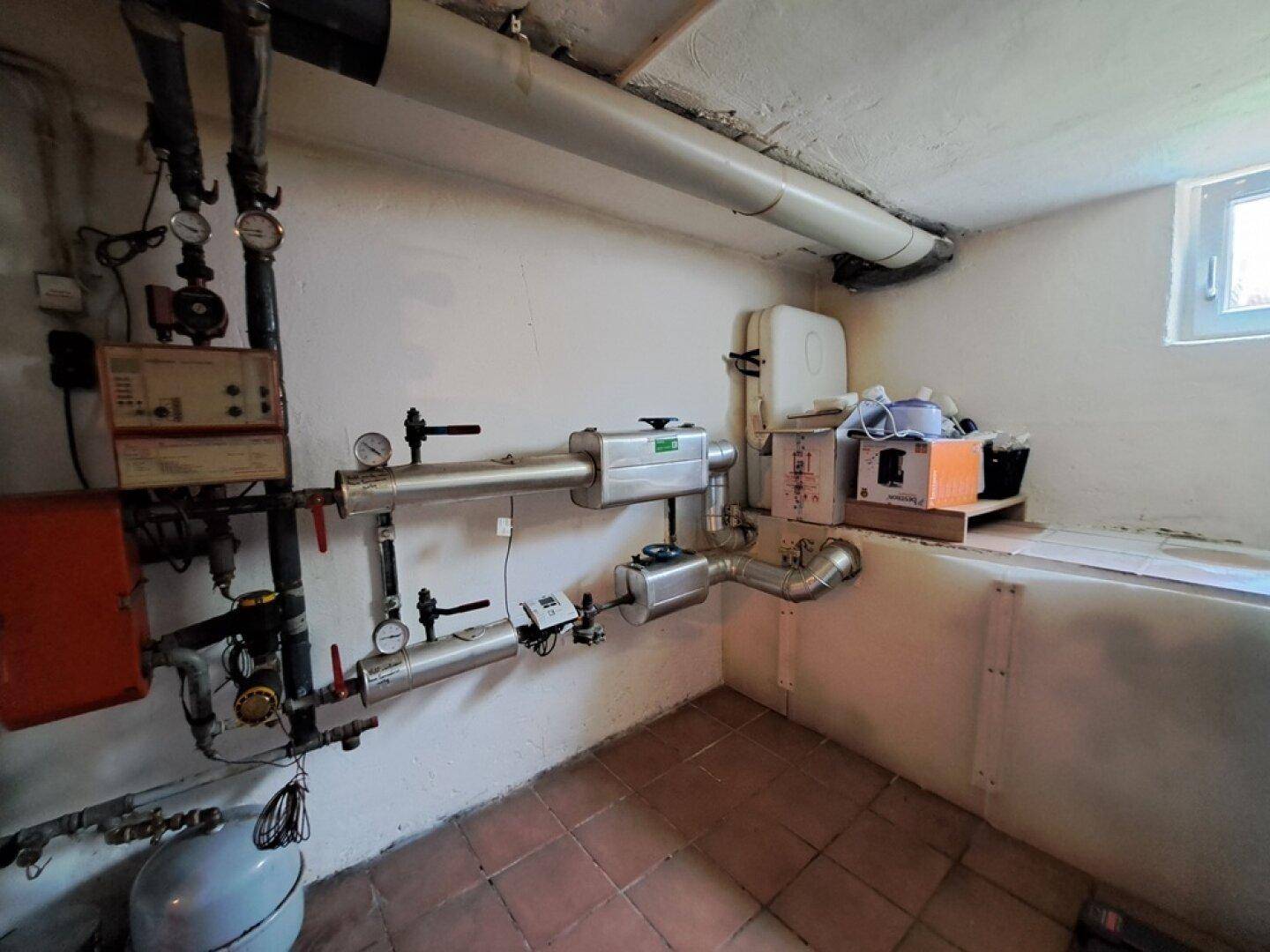 Technischer Raum im Keller mit komplexen Rohrleitungen und Heizungsinstallationen.