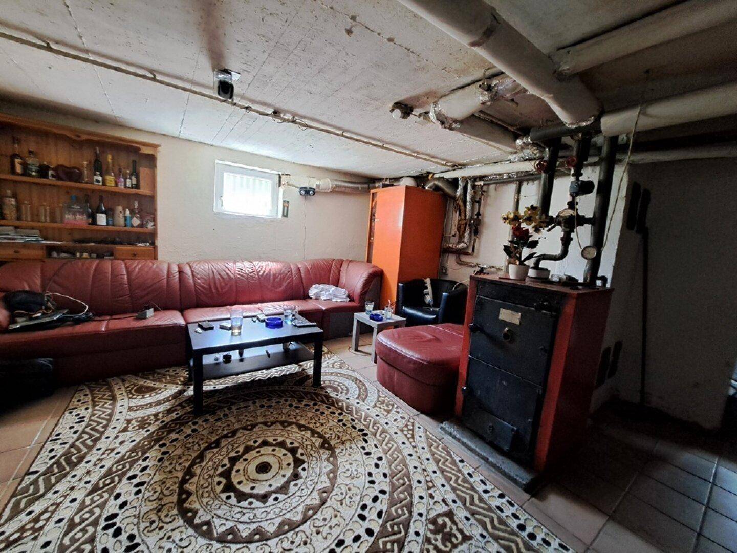 Kellerraum als Wohnbereich genutzt mit Sofa, Teppich und Heizungsanlage.