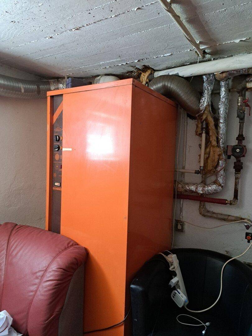 Heizungsraum im Keller mit großem Heizkessel und sichtbaren Rohrleitungen.