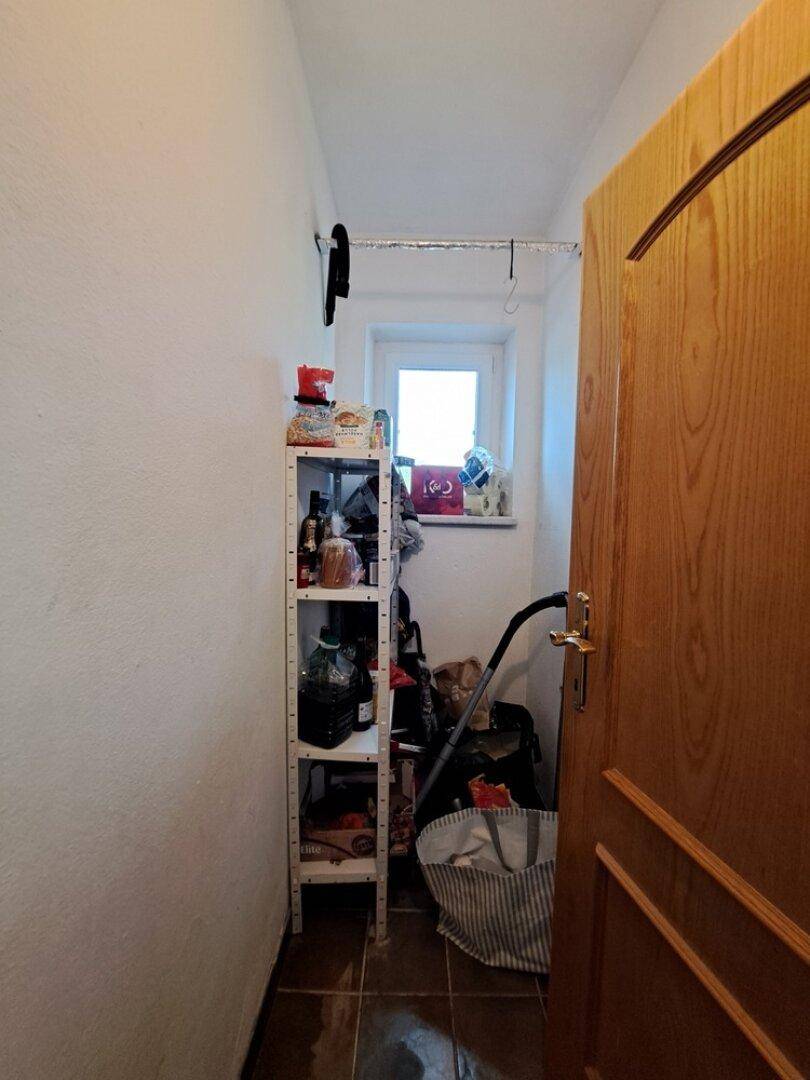 Praktischer Abstellraum mit Regal, Fenster und Stauraum für Haushaltsgegenstände.