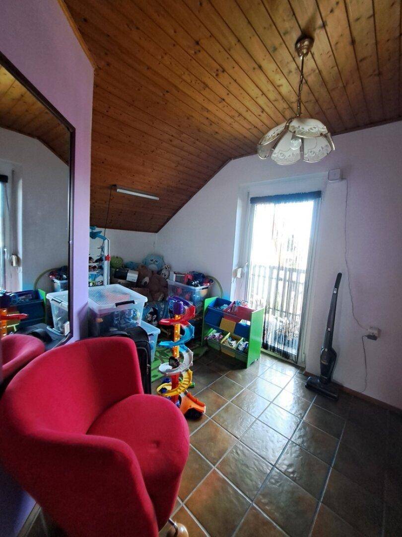 Dachgeschossraum mit Fliesenboden, Balkonzugang und Stauraum für diverse Gegenstände.