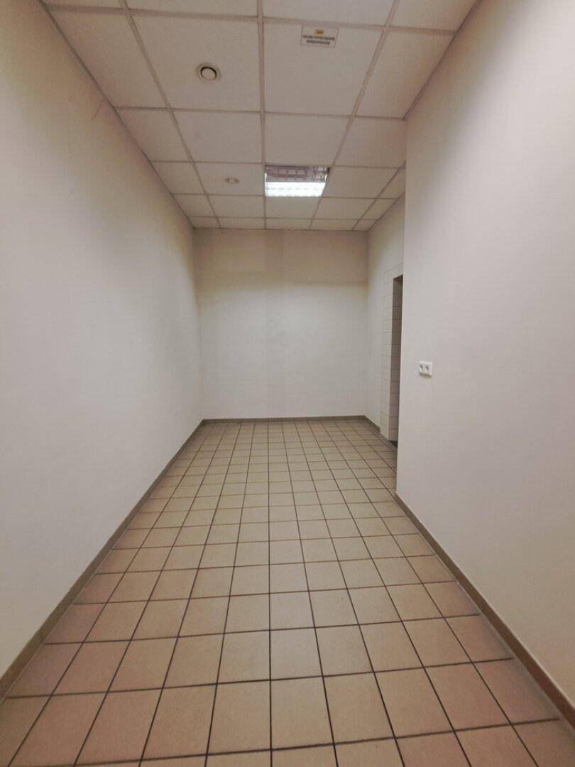 Langer Flur mit Fliesenboden und weißen Wänden, der zu weiteren Räumen führt.