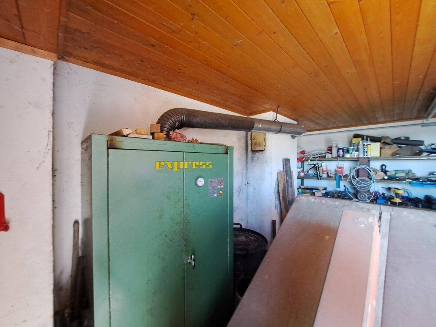 Technikraum oder Werkstatt mit Heizungsanlage und Holzpaneeldecke, ideal für Lagerung.