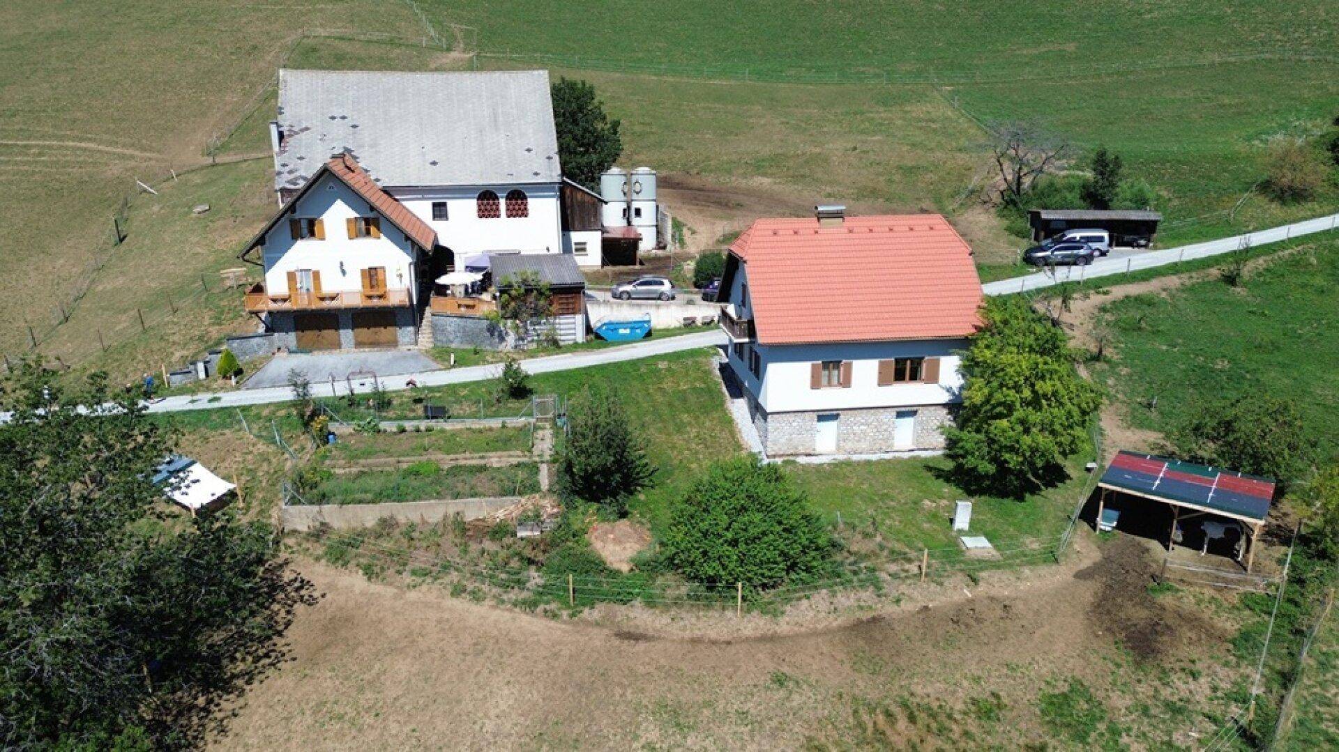 Luftaufnahme des gesamten Anwesens mit zwei Gebäuden und umliegenden Grünflächen.