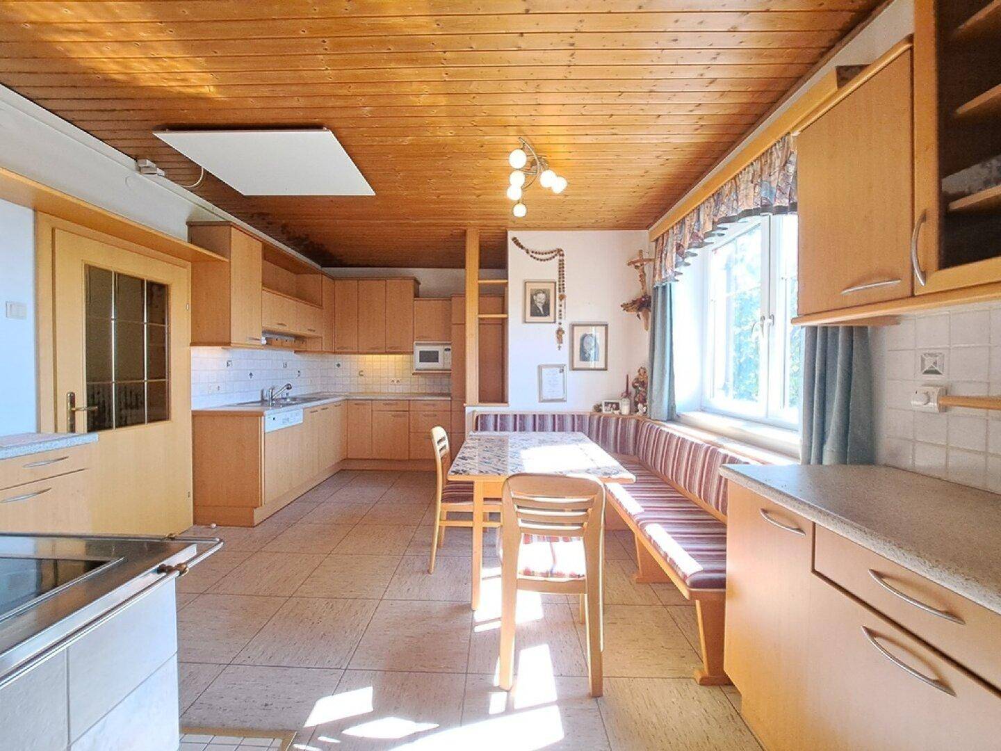 Gemütliche Wohnküche mit Holzbalkendecke, Essbereich und traditionellen Elementen.