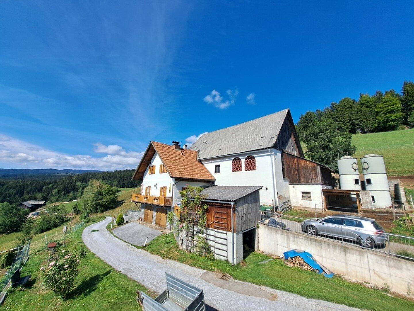Weitläufige Ansicht des Anwesens mit Haupthaus, Scheune und ländlicher Umgebung.