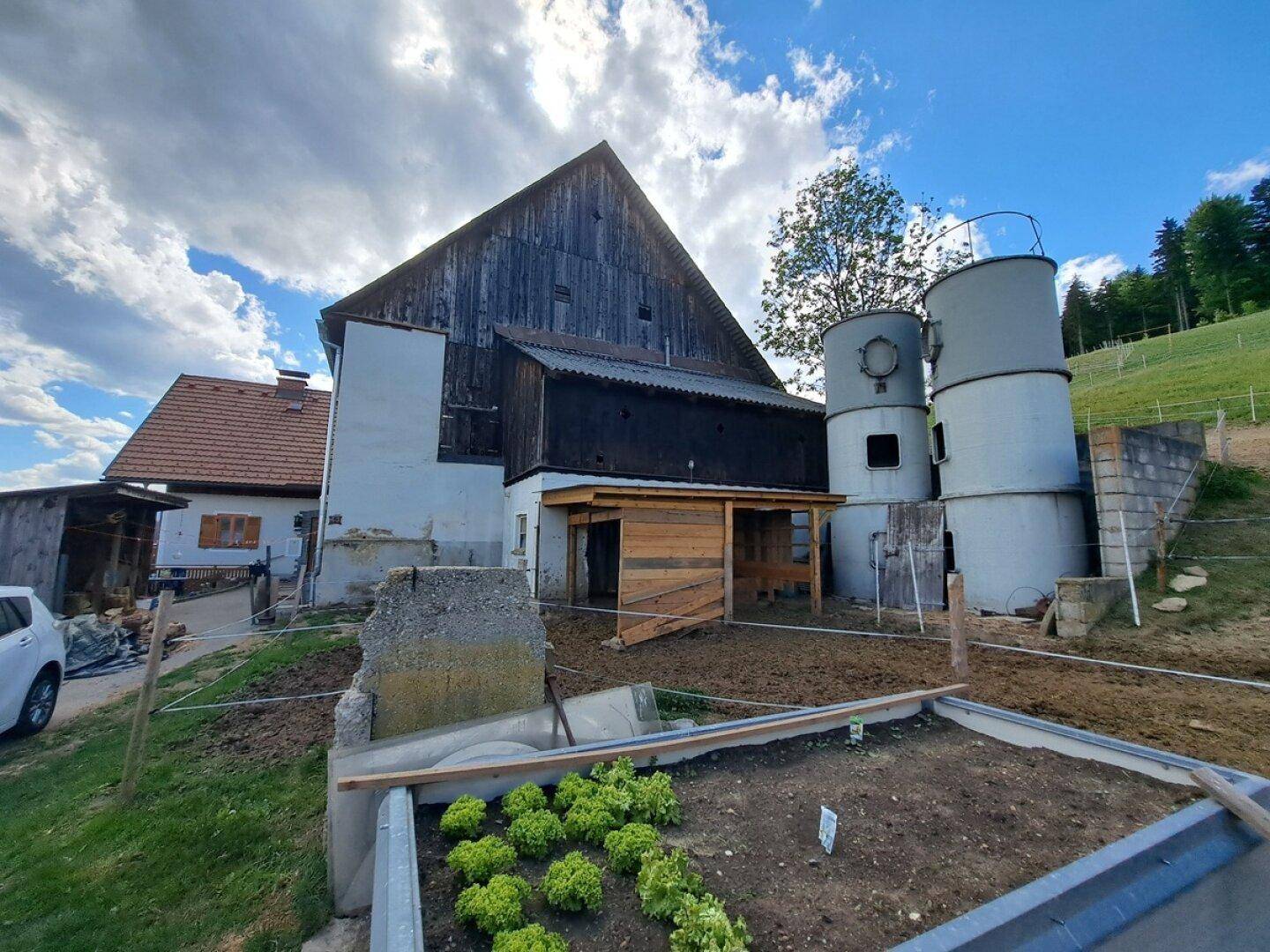 Anwesen mit Haupthaus, Scheune und einem Hochbeet im Gartenbereich.