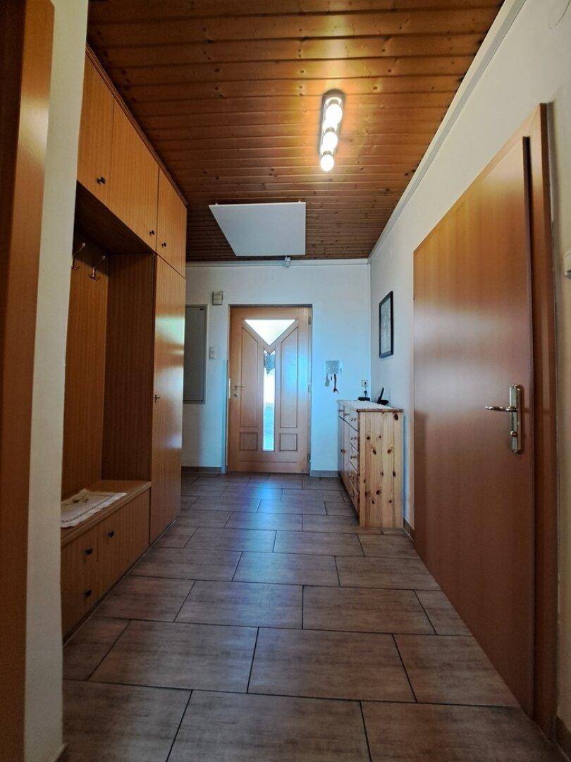 Heller Flur mit Holzdecke, Fliesenboden und Einbauschränken.