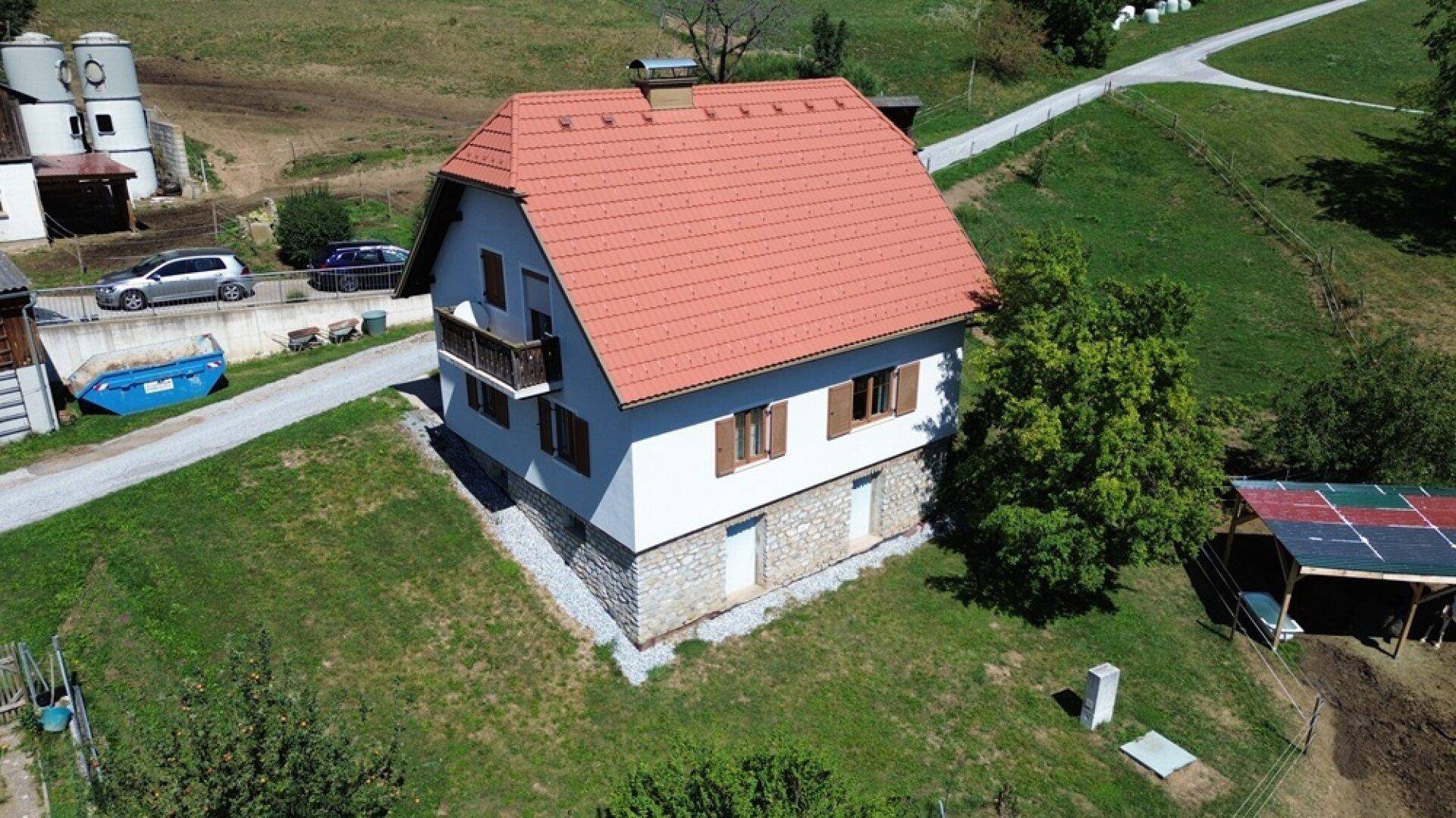 Luftaufnahme eines Einfamilienhauses mit rotem Ziegeldach und gepflegtem Gartenbereich.