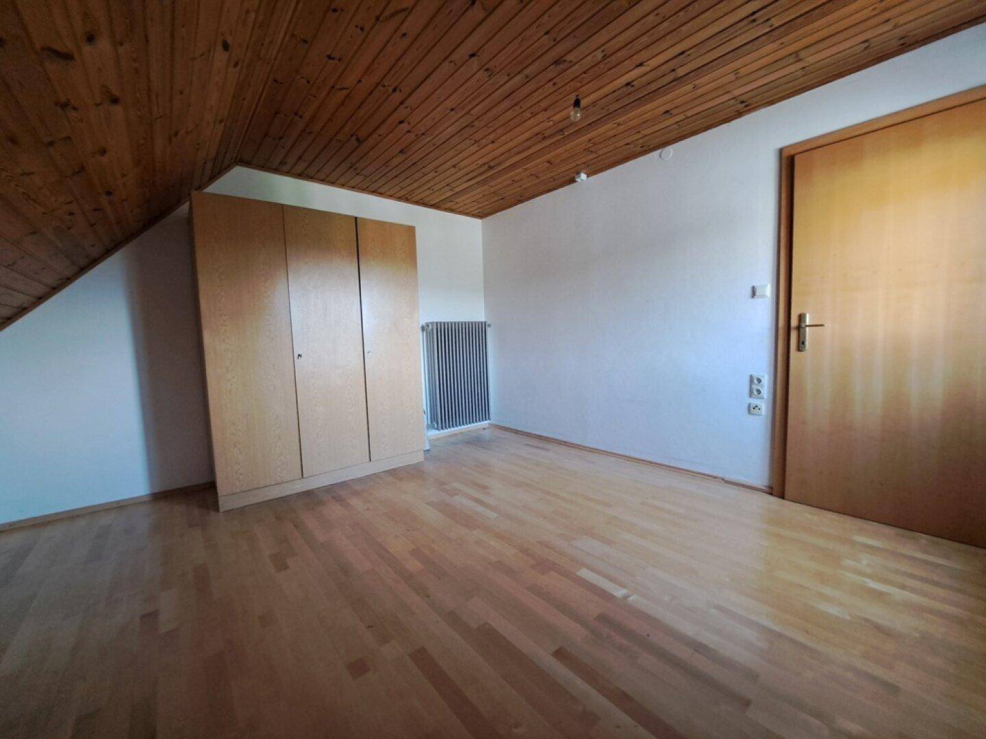 Schlafzimmer im Dachgeschoss mit Holzdecke, Holzboden und Kleiderschrank.
