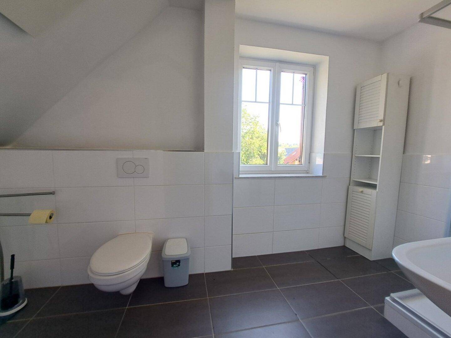 Badezimmer im Dachgeschoss mit WC, Waschbecken und Fenster.