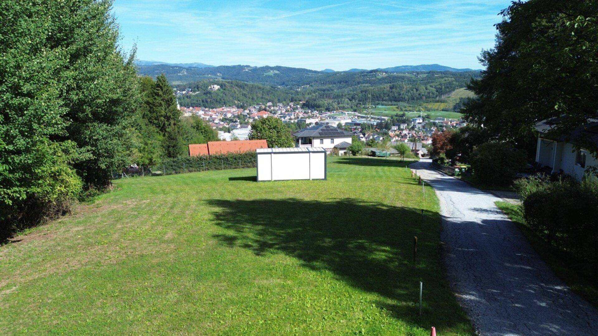 Weitläufiges grünes Grundstück mit Blick auf eine Stadt und die umliegende Berglandschaft.