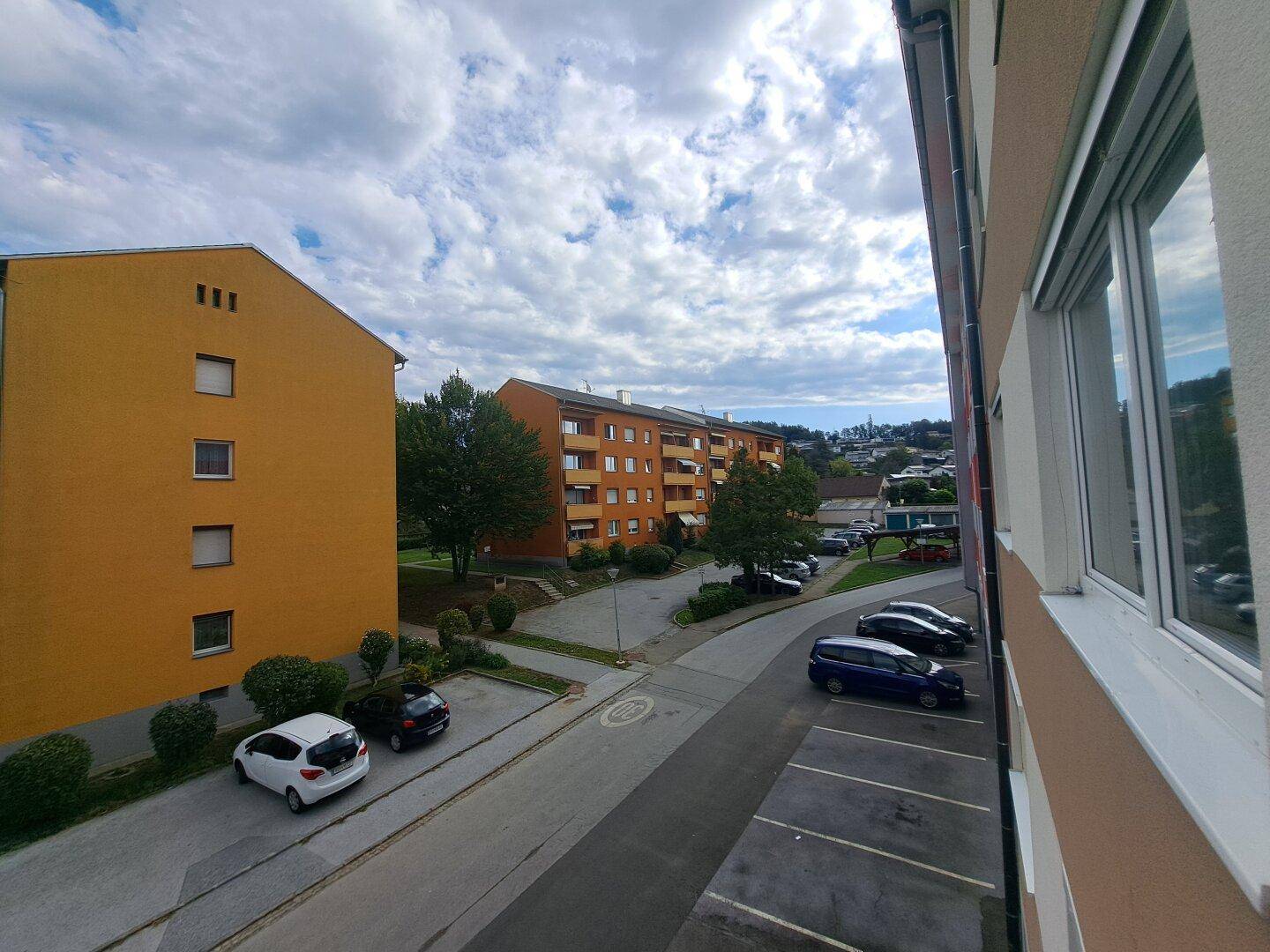 Panoramablick vom Balkon auf die Wohngegend, Straße und ferne Hügel unter bewölktem Himmel.