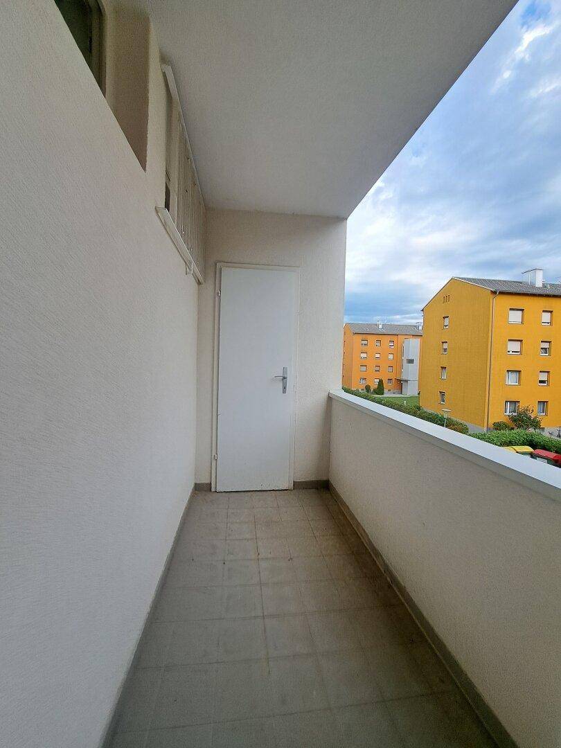 Kleiner Balkon mit Fliesenboden und Blick auf die umliegenden Wohngebäude.