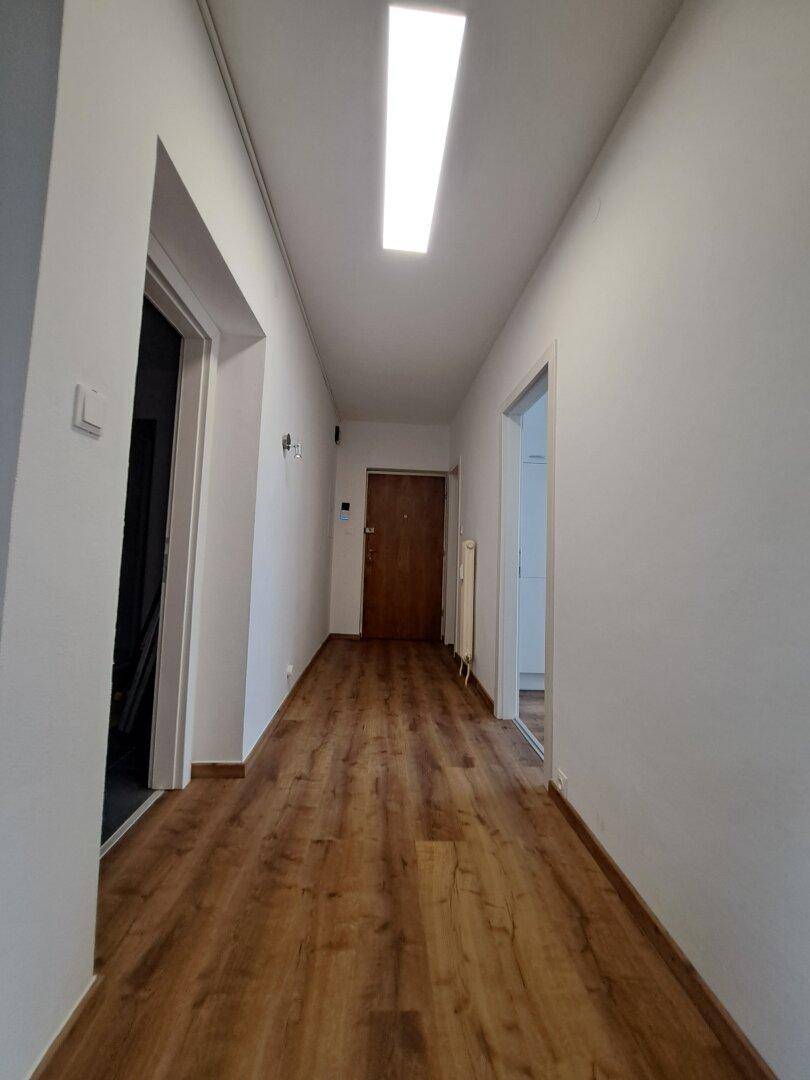 Heller Flur mit Laminatboden und weiß gestrichenen Wänden, der zu den verschiedenen Räumen führt.