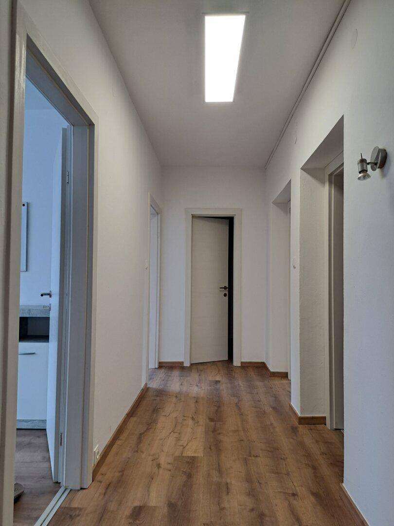 Langer, heller Flur mit Laminatboden und mehreren Türen zu den angrenzenden Zimmern.