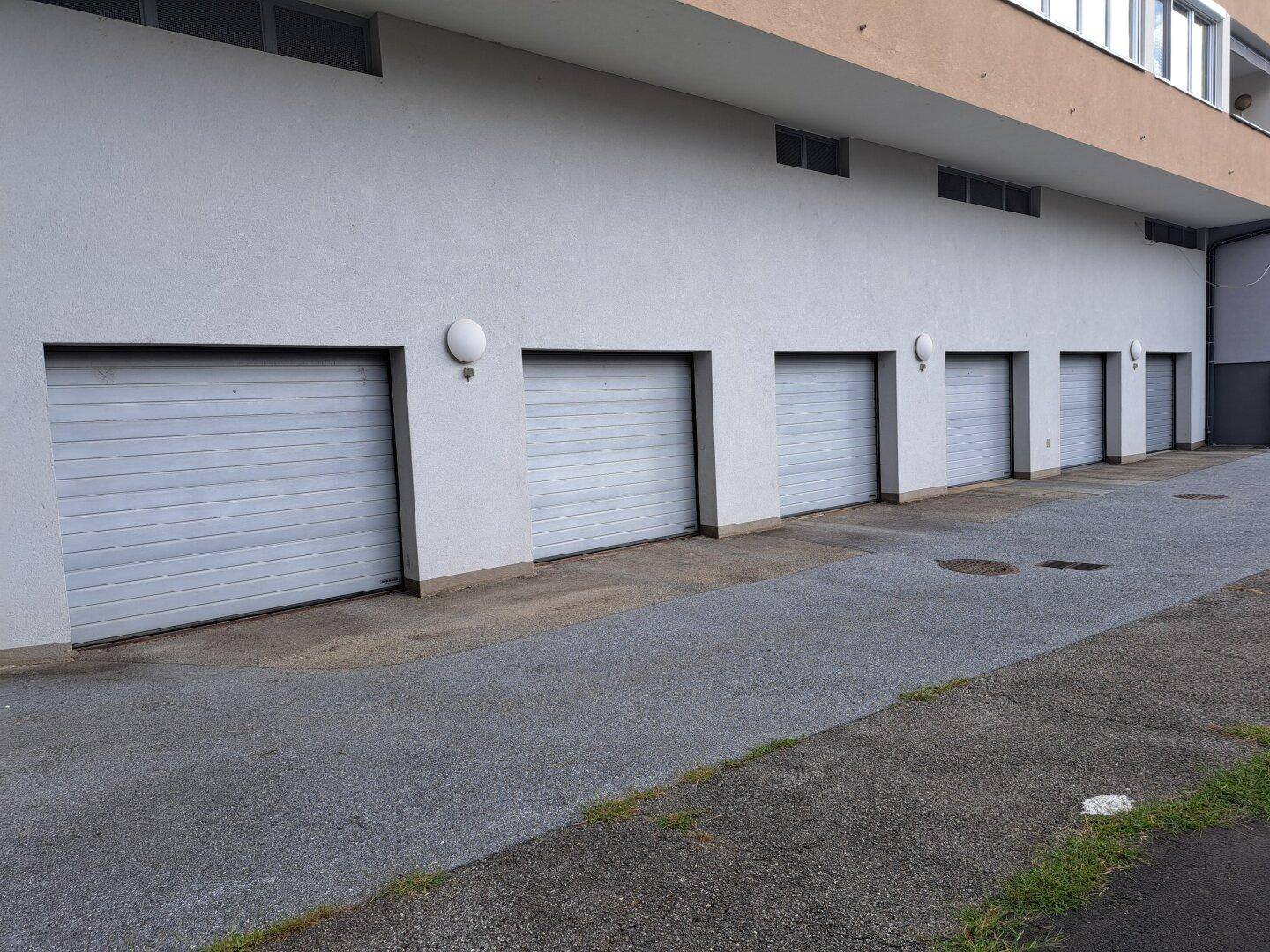 Reihe von Garagentoren an der Gebäudeseite, die Parkmöglichkeiten bieten.