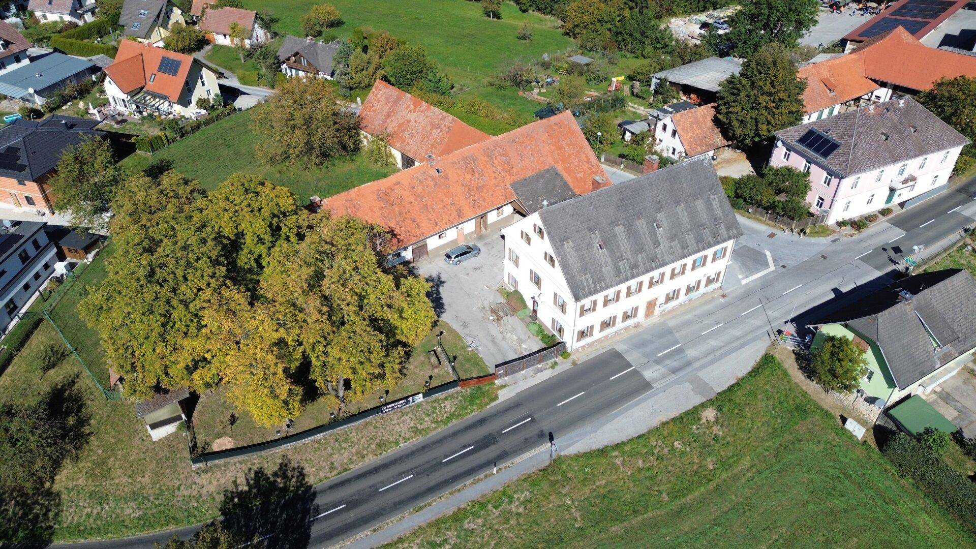 Weitläufige Luftaufnahme eines Anwesens mit einem großen Feld, umgeben von ländlicher Bebauung und Straßen.