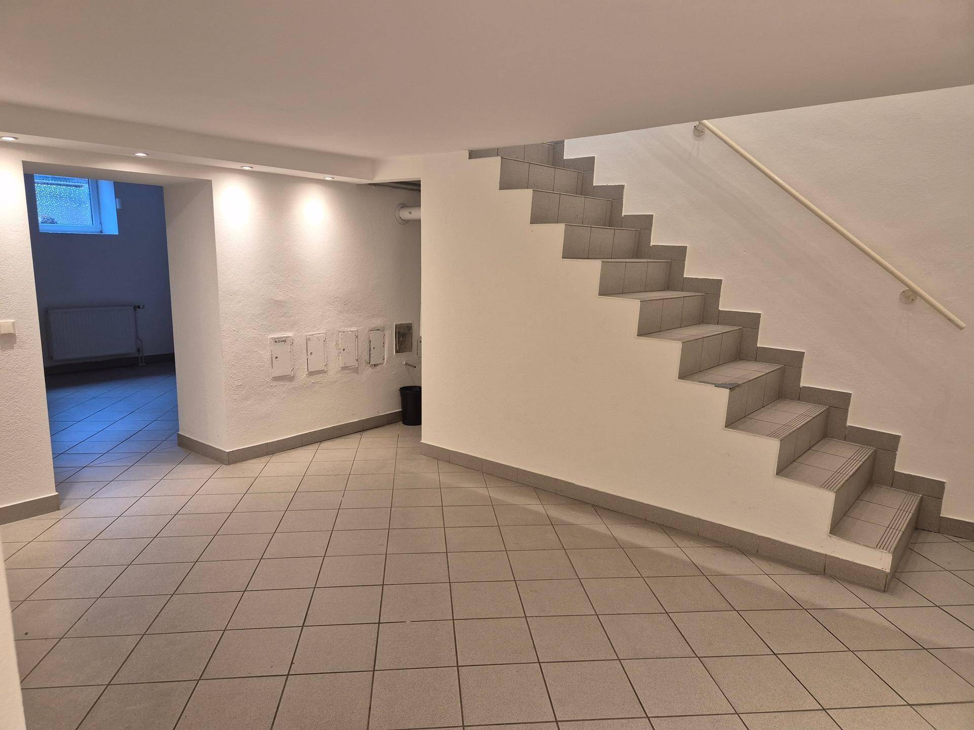 Geräumiger Eingangsbereich mit Treppe und Fliesenboden, gut beleuchtet durch Deckenspots.