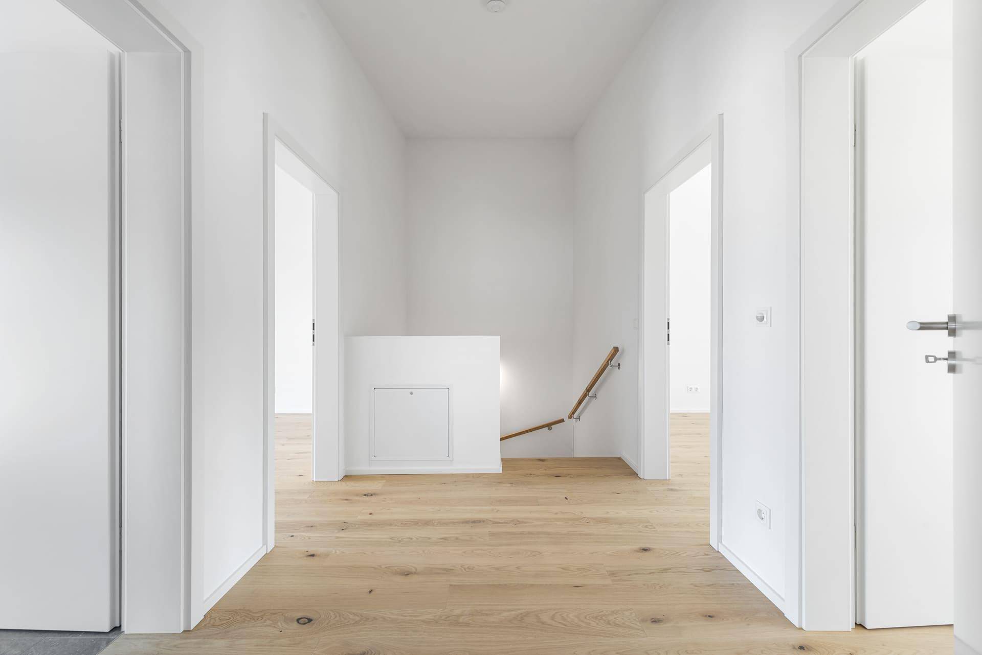 Heller Flur im Obergeschoss mit Holzboden und Zugang zu mehreren Zimmern.