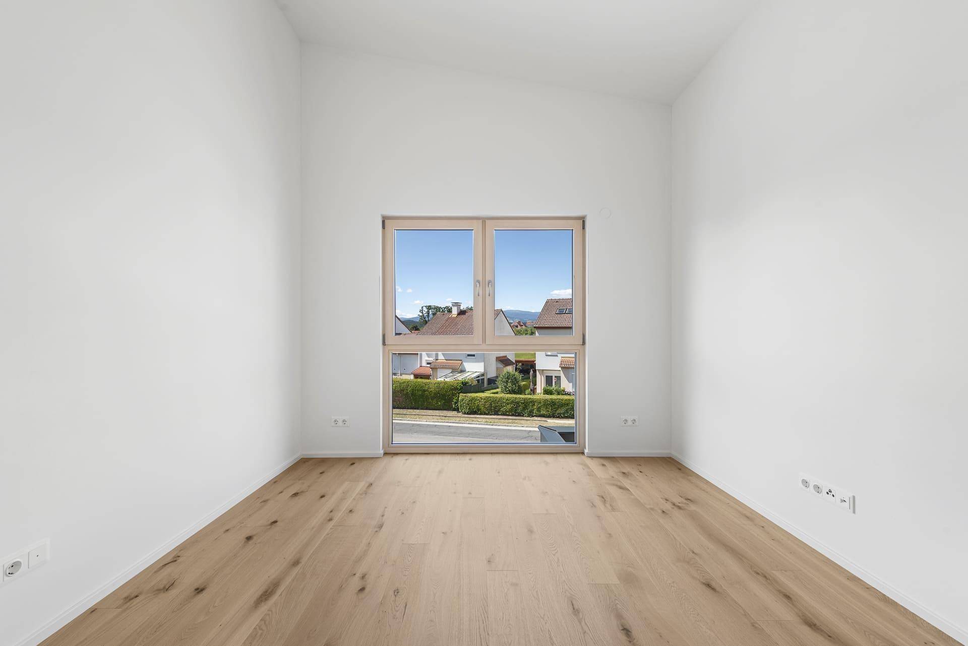 Helles Zimmer mit Holzboden und weitem Blick über die Landschaft und die Berge.