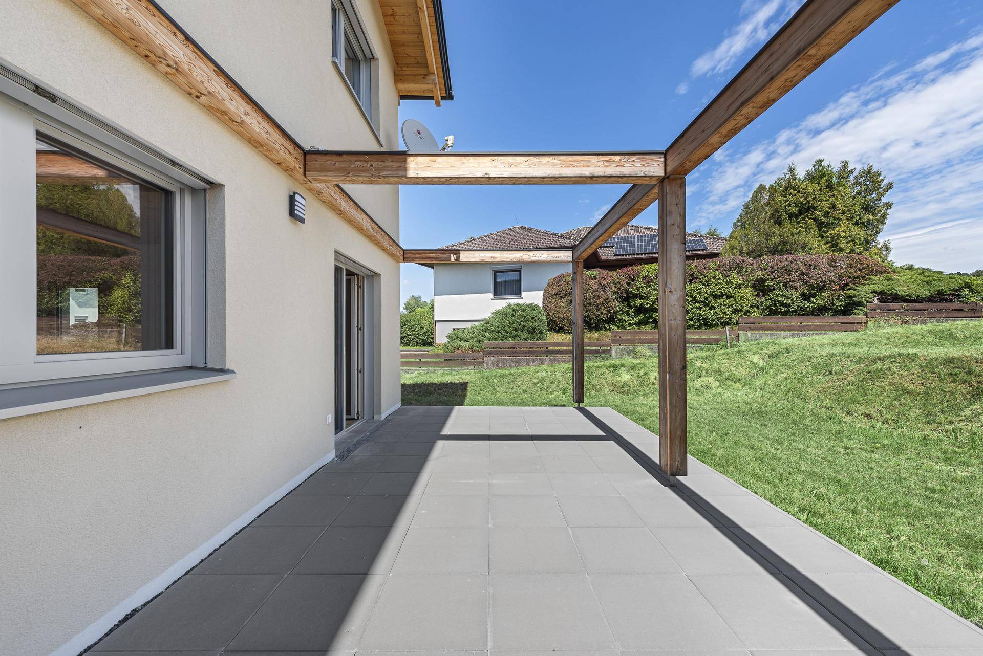 Weitläufige Terrasse mit Pergola und Blick auf den Garten und die Umgebung.