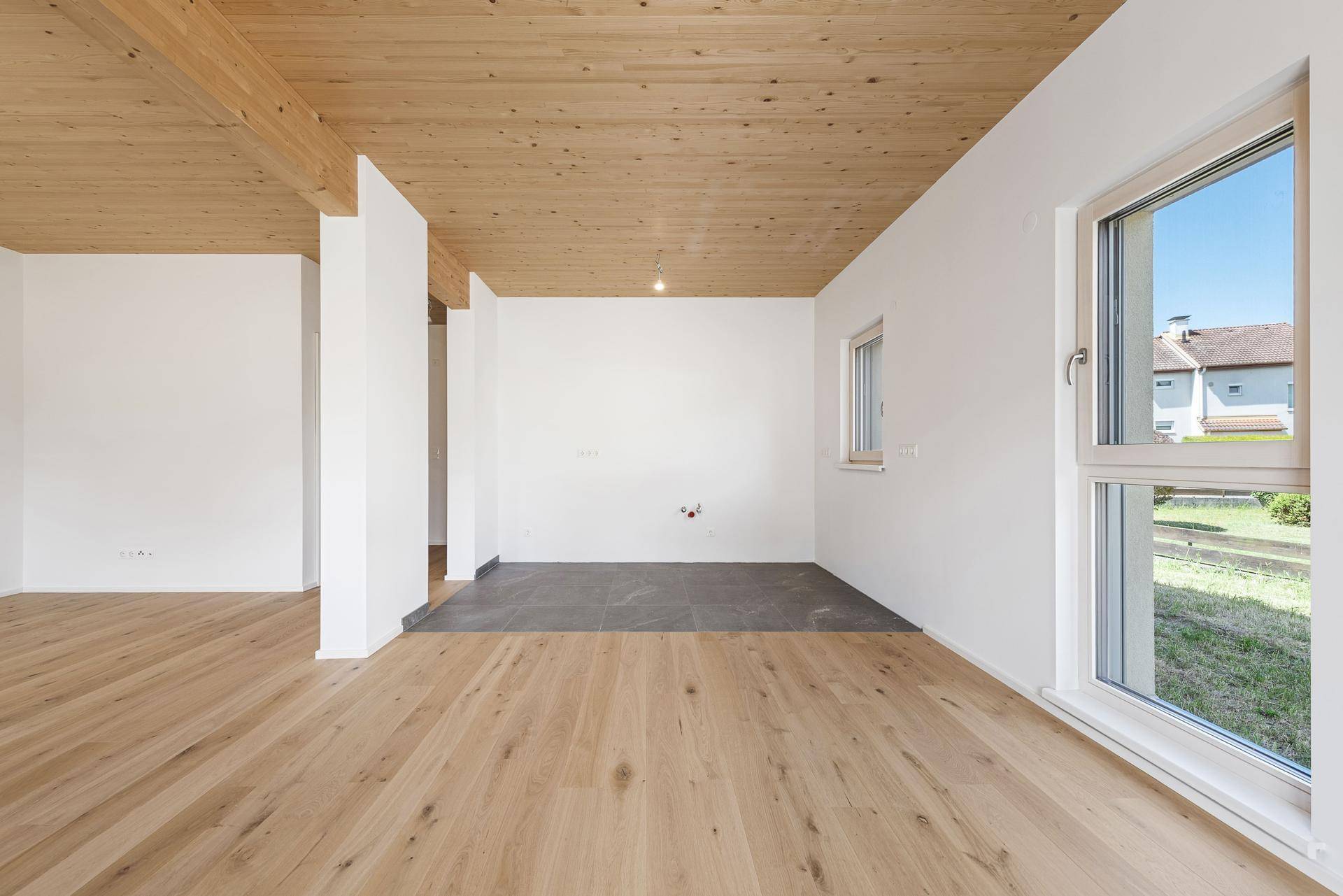 Heller Wohnbereich mit Holzboden und einem gefliesten Bereich, ideal für eine offene Küche.