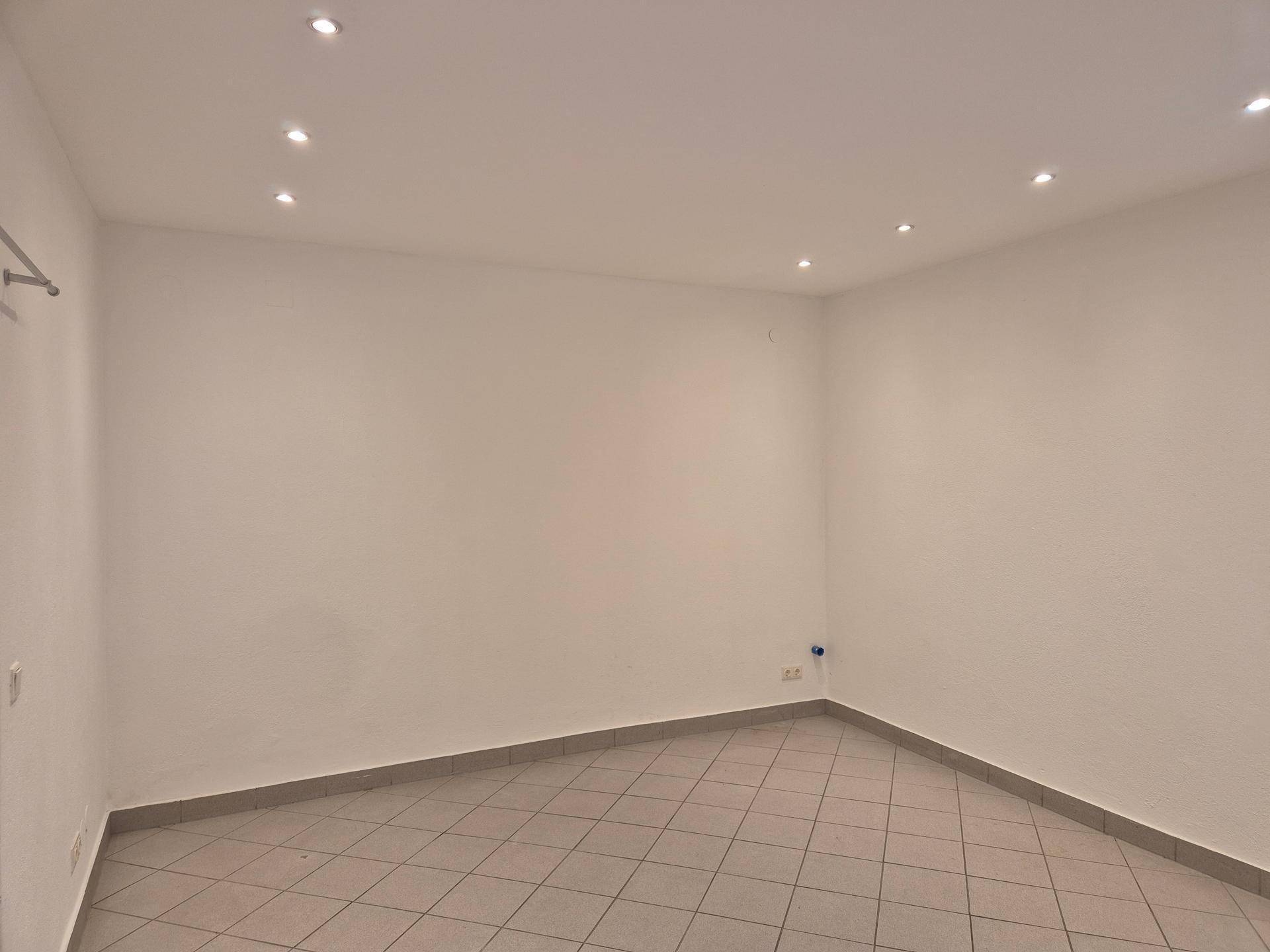 Heller Raum im Untergeschoss mit Fliesenboden und Deckenspots, ideal als Lager oder Büro.