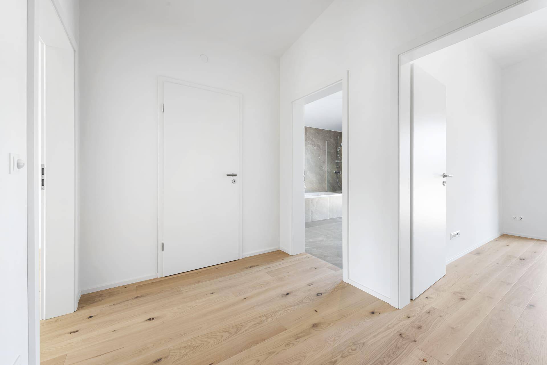 Geräumiger Flur mit hellem Holzboden und Türen zu den angrenzenden Wohnräumen.