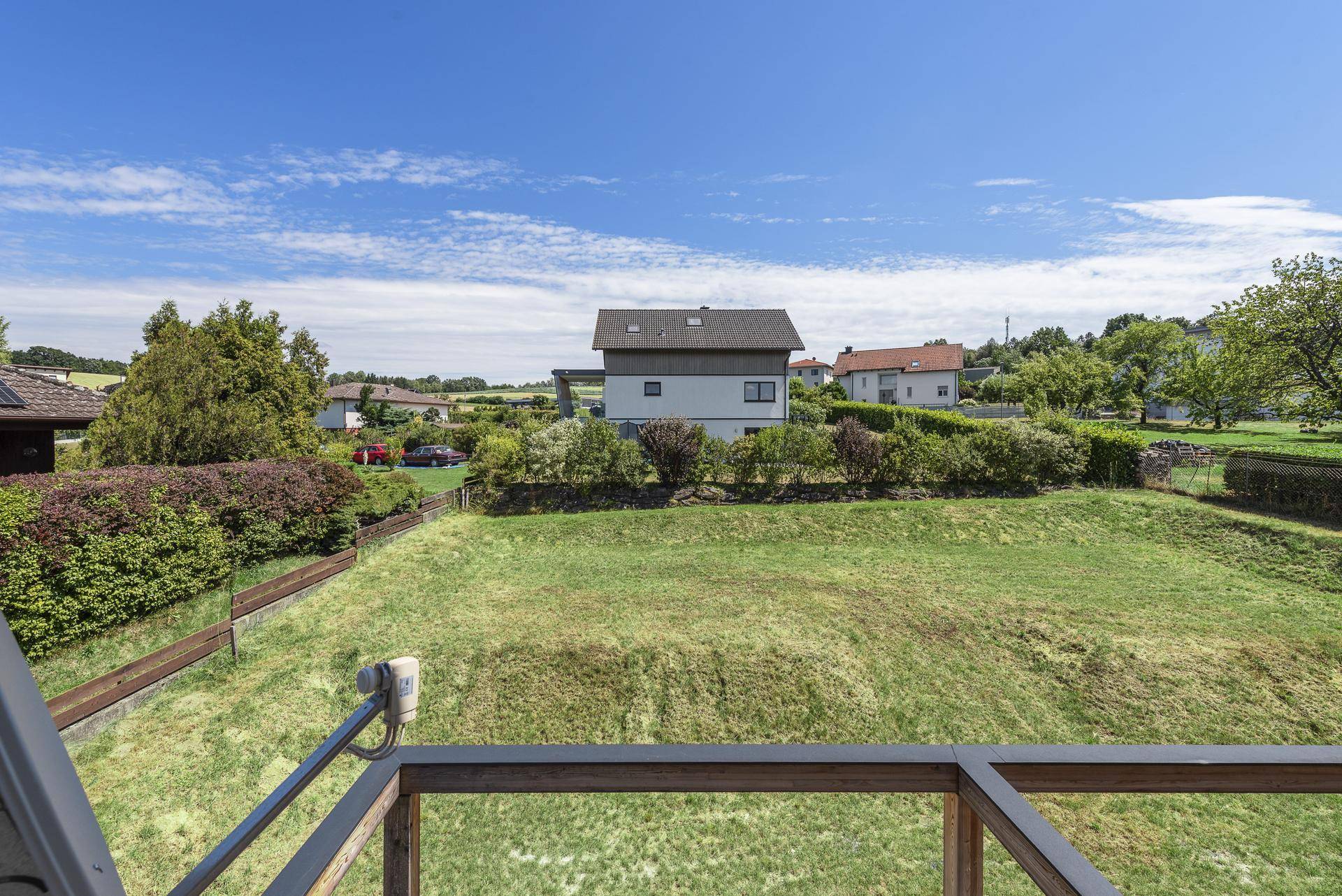 Weitläufiger Blick über eine große Grünfläche, umliegende Häuser und die Landschaft.