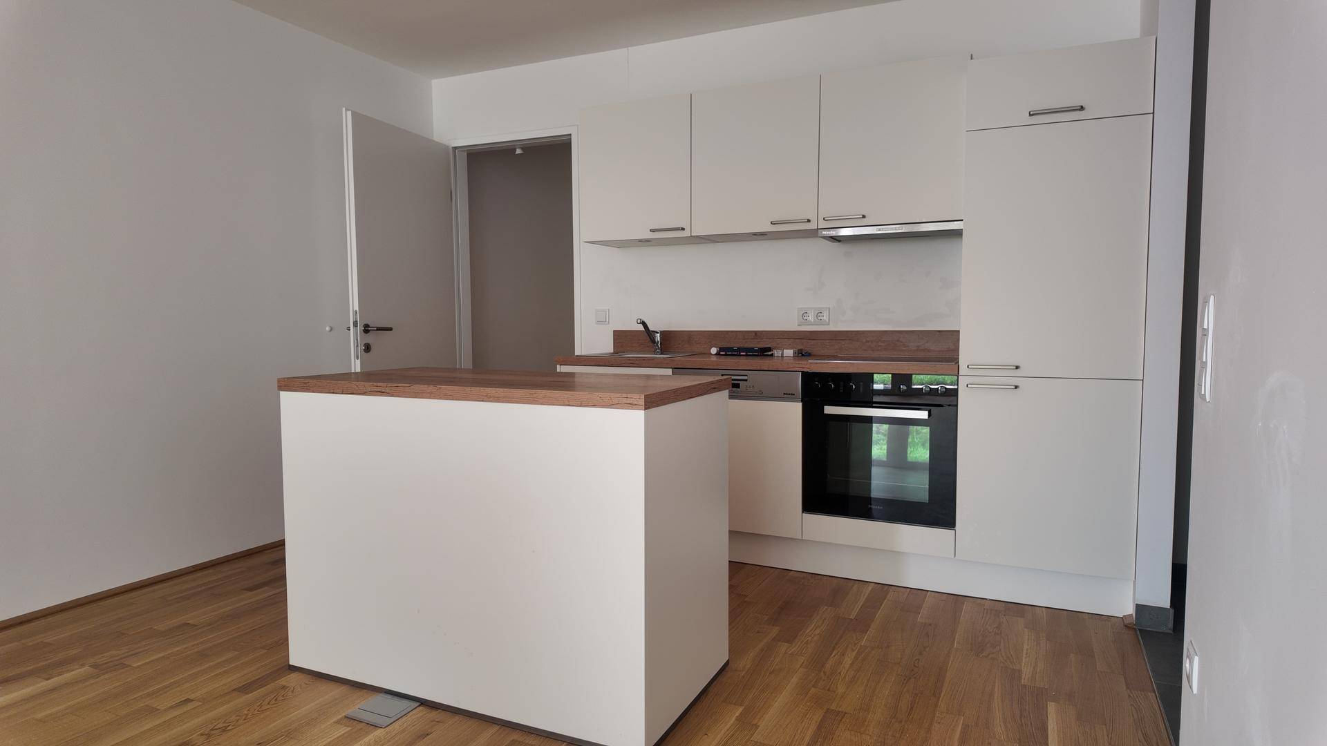Moderne Küche mit weißen Schränken, Holz-Arbeitsplatte, Backofen und einer praktischen Kücheninsel.