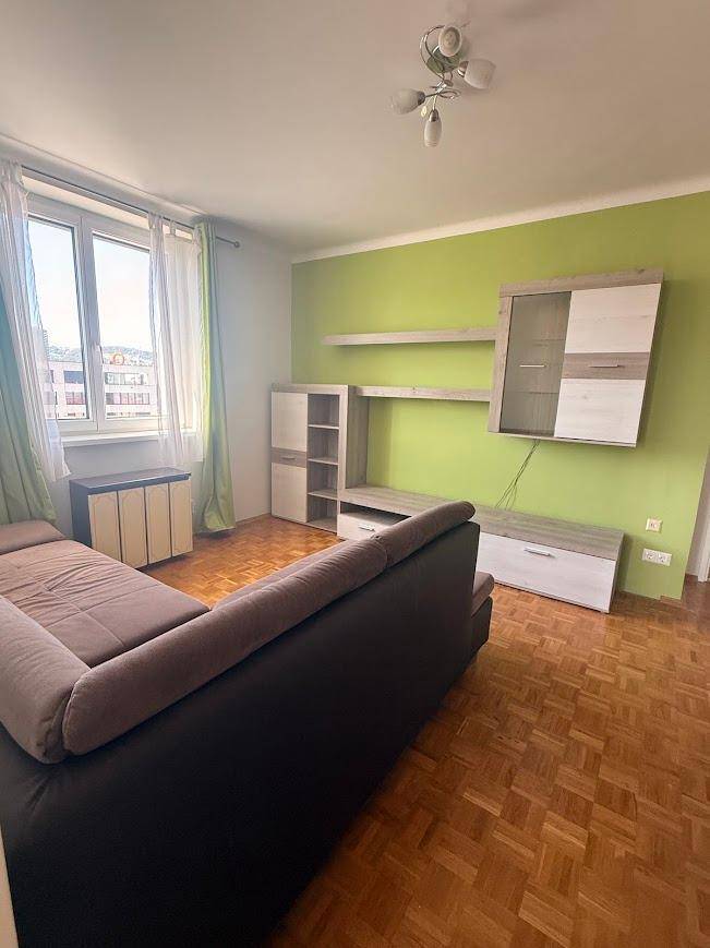 Wohnzimmer mit grüner Akzentwand, modernem Medienmöbel und klassischem Parkettboden.