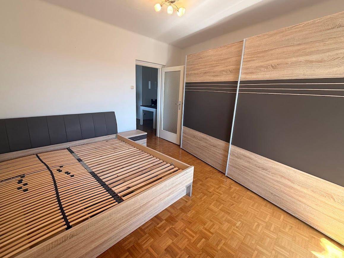 Schlafzimmer mit hellem Parkettboden und großem Schiebetürenschrank.