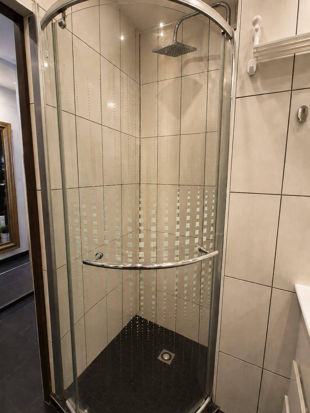 Moderne Duschkabine mit Regenduschkopf und hellen Fliesen im Badezimmer.