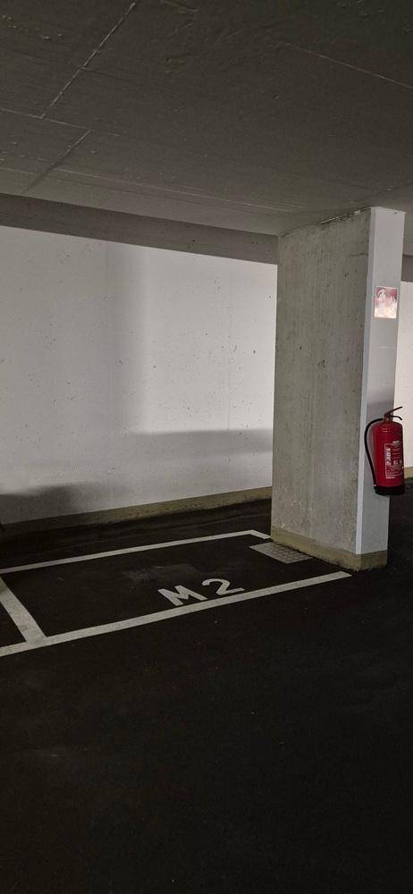 Tiefgaragenstellplatz M2 mit Betonpfeiler und Feuerlöscher an der Wand.