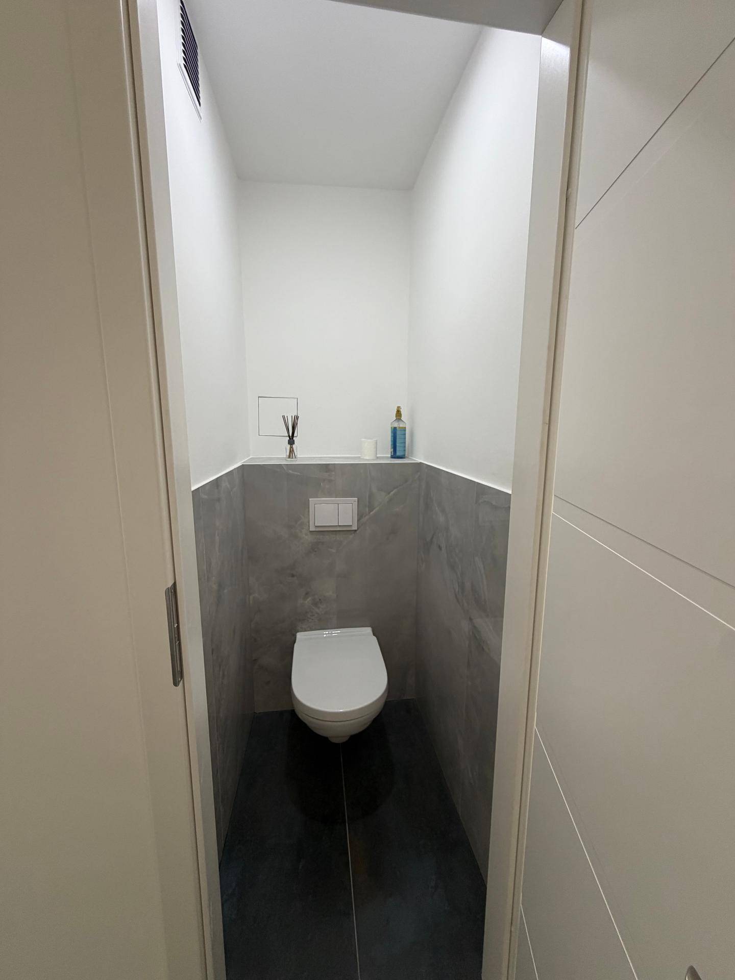 Kleines, modernes Gäste-WC mit wandhängender Toilette und stilvollen grauen Fliesen.