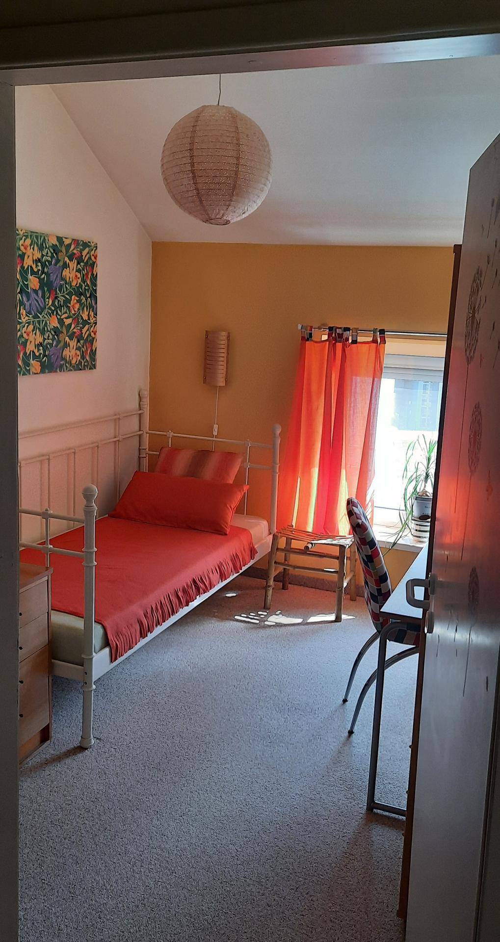 Gemütliches Schlafzimmer mit Dachschräge, gelber Wand und hellem Teppichboden.
