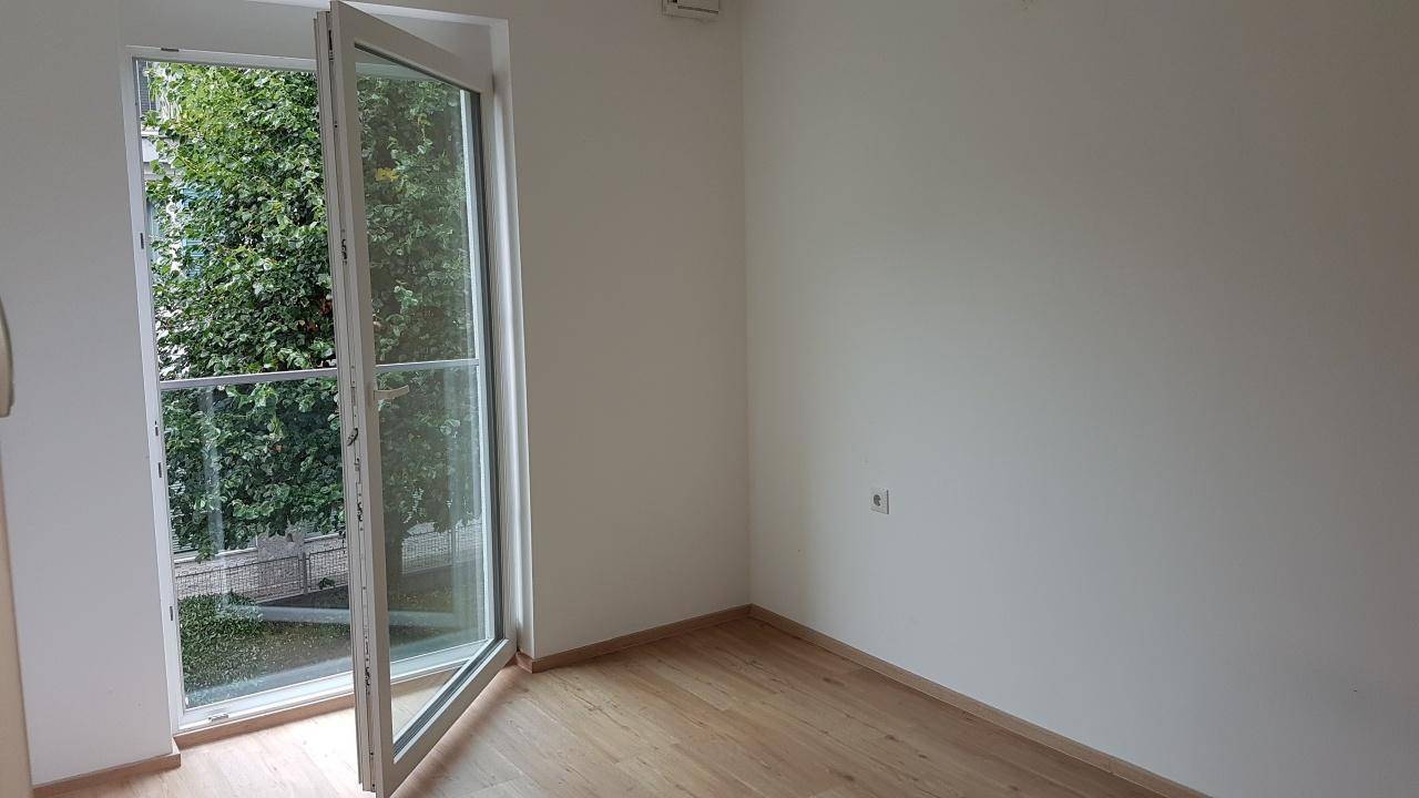 Helles Zimmer mit Laminatboden und direktem Zugang zu einem kleinen Balkon.
