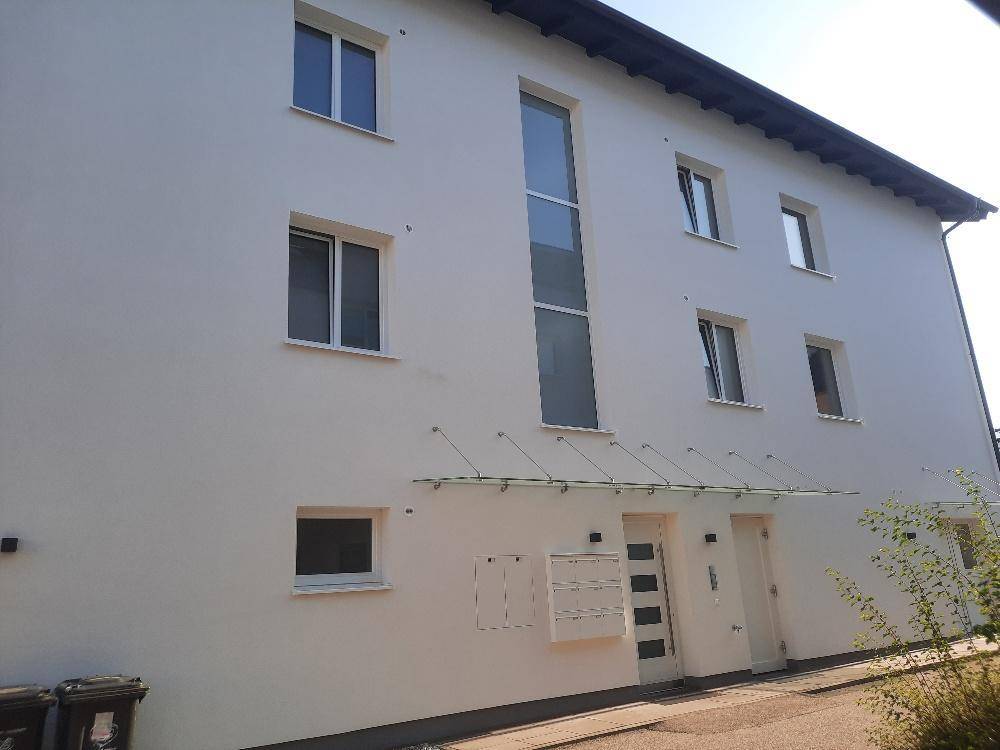 Eingangsbereich eines modernen Wohnhauses mit großen Fenstern und Vordach.
