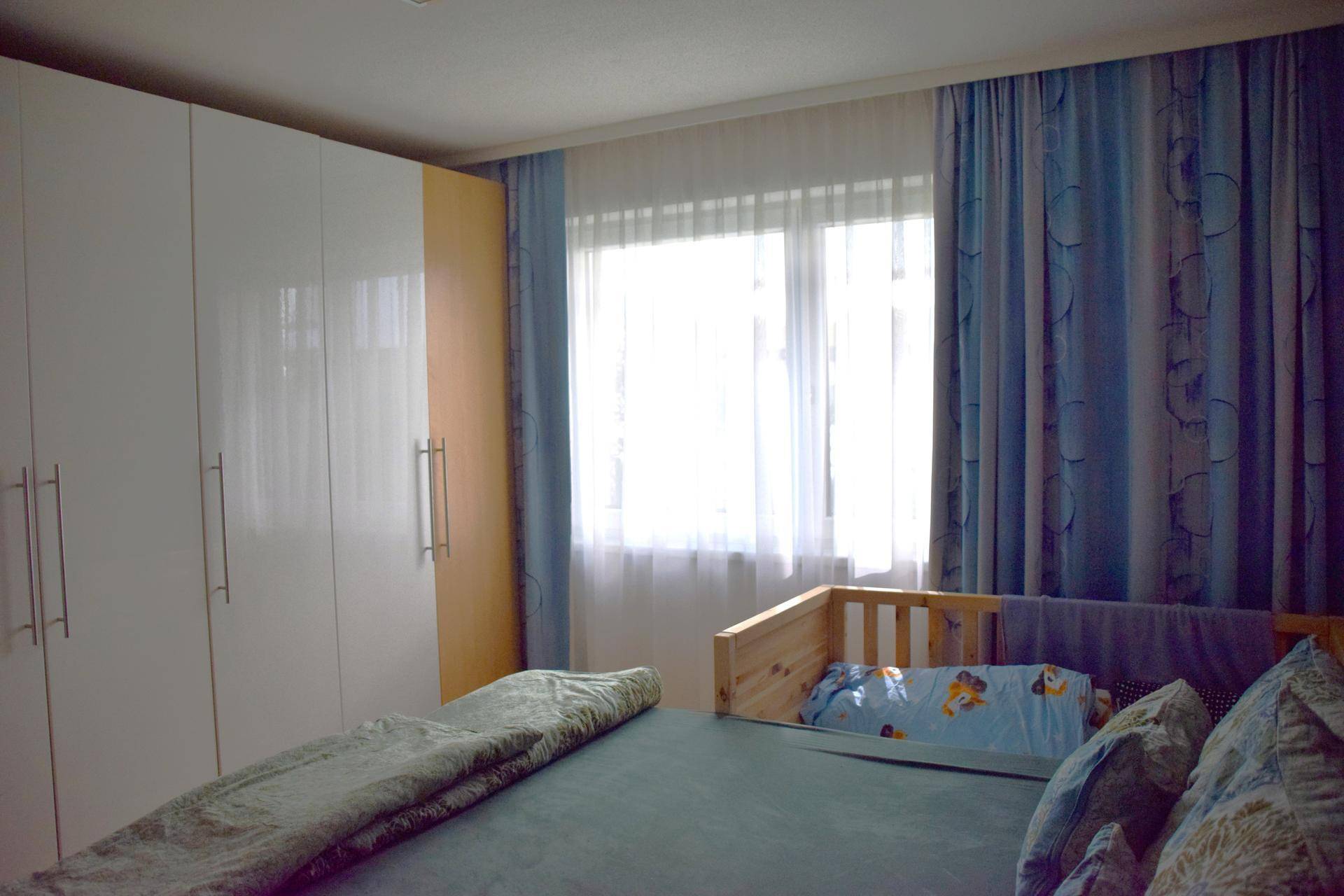 Schlafzimmer mit geräumigen weißen Kleiderschränken und hellem Fensterbereich.