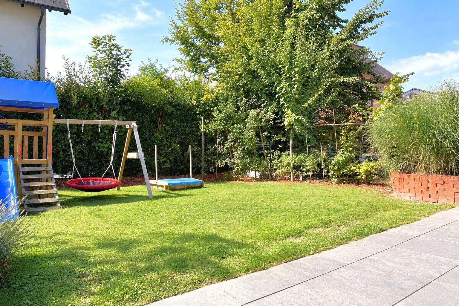 Großer, gepflegter Garten mit Rasenfläche, Spielplatz und üppiger Bepflanzung.