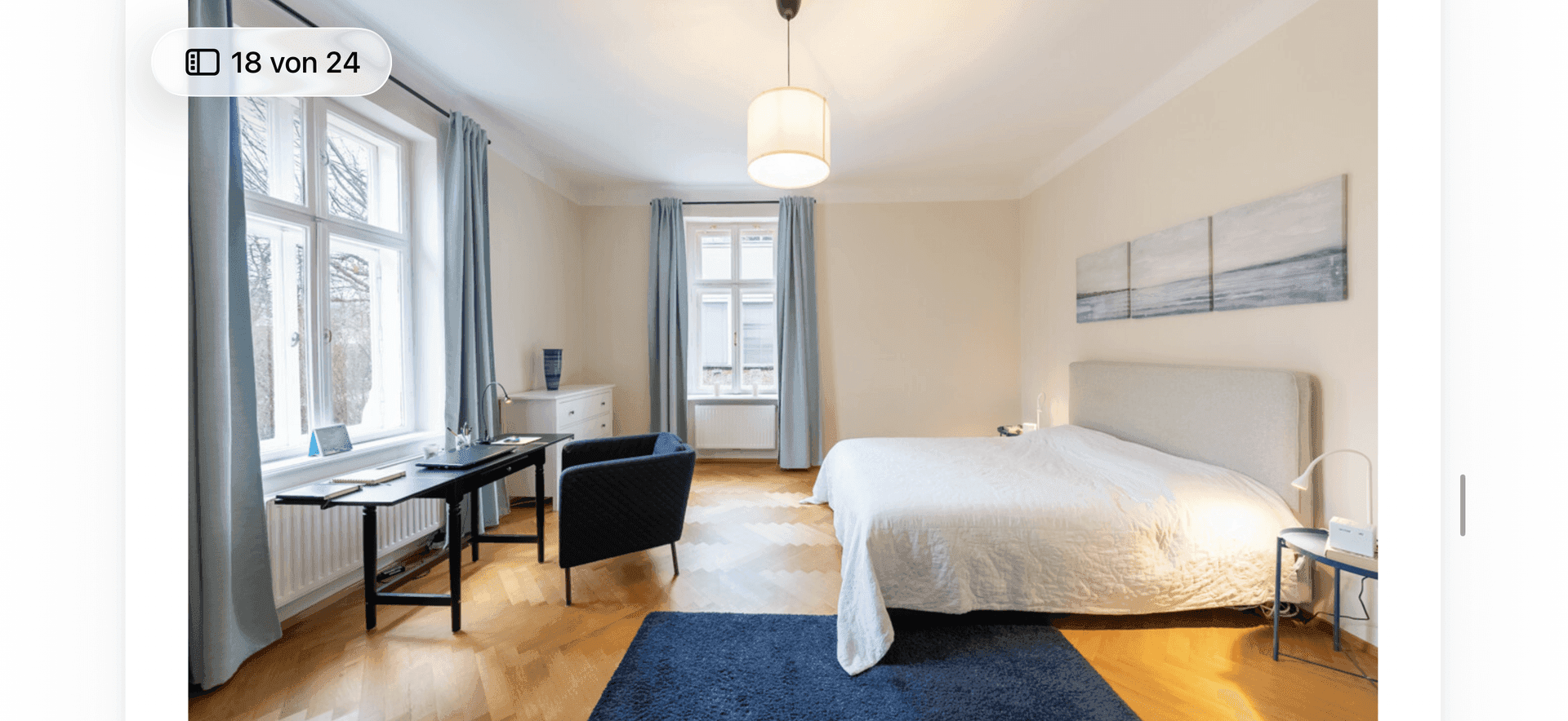 Großes Schlafzimmer mit Doppelbett, Schreibtisch und Fischgrätparkett.