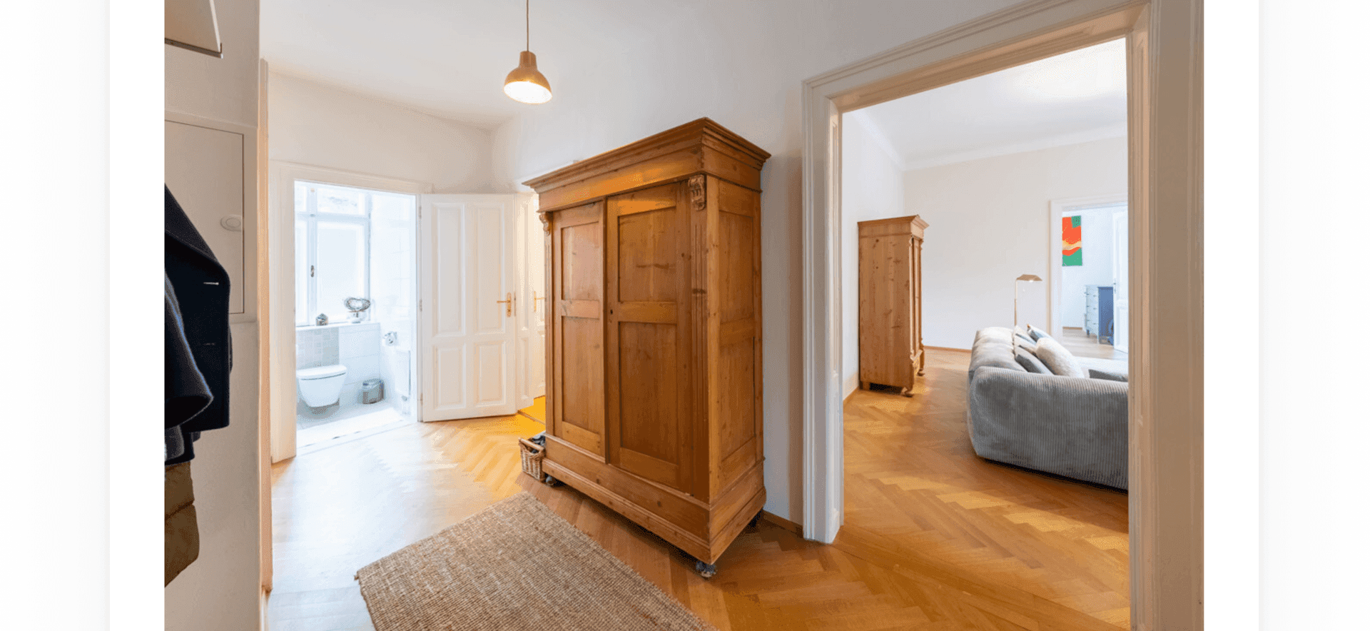 Geräumiger Flur mit Holzschrank, Fischgrätparkett und Zugang zu weiteren Räumen.