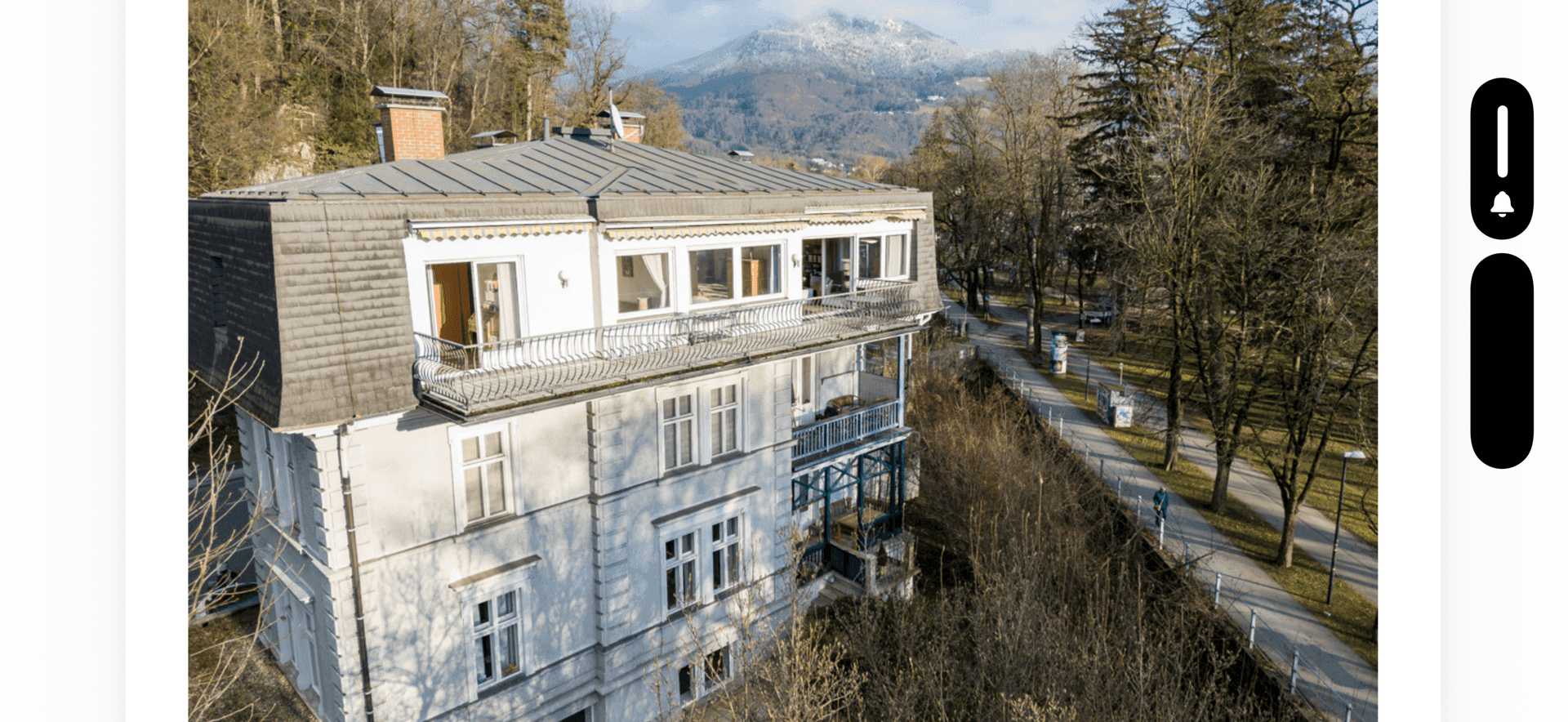 Historisches Gebäude mit Balkonen und Blick auf die umliegende Natur und Berge.