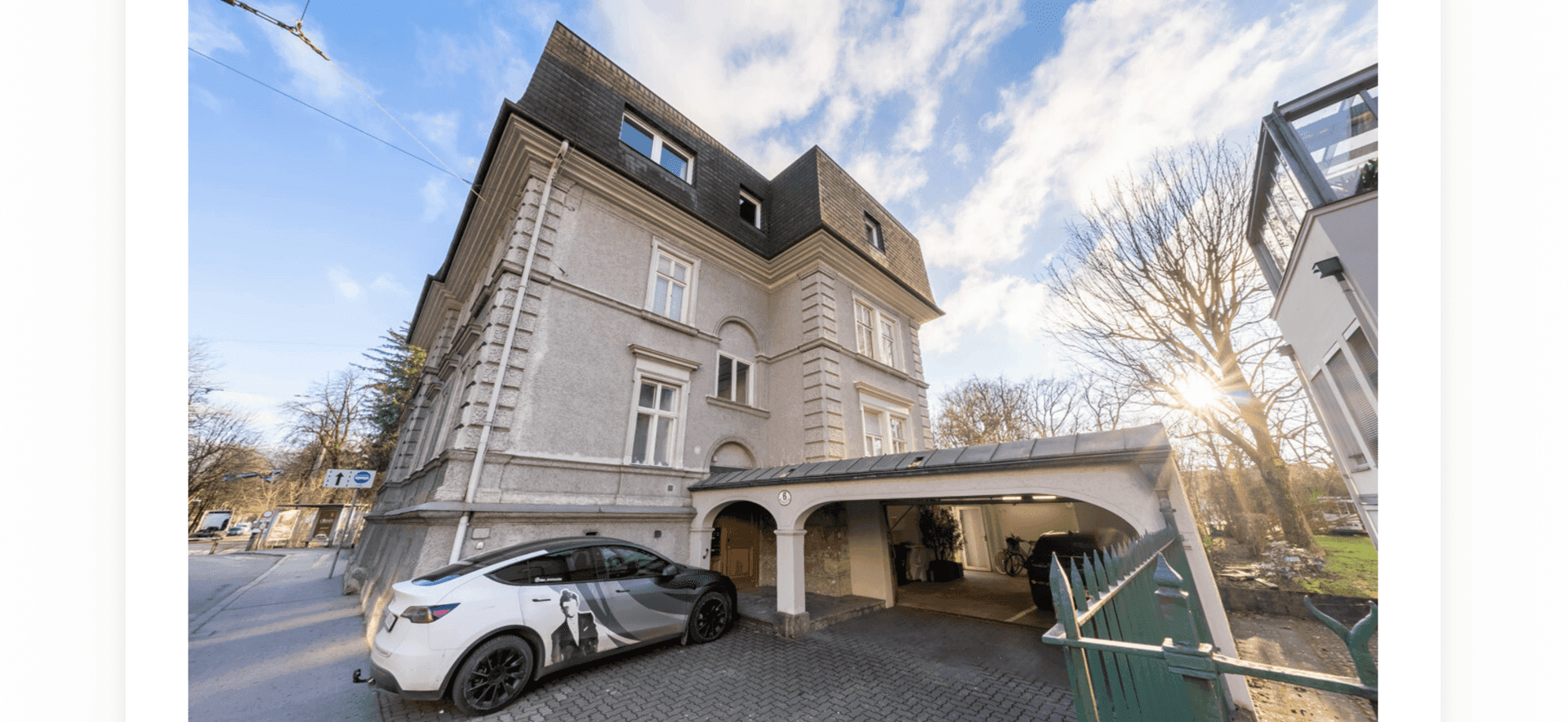 Elegante Fassade eines historischen Gebäudes mit Carport und gepflasterter Zufahrt.