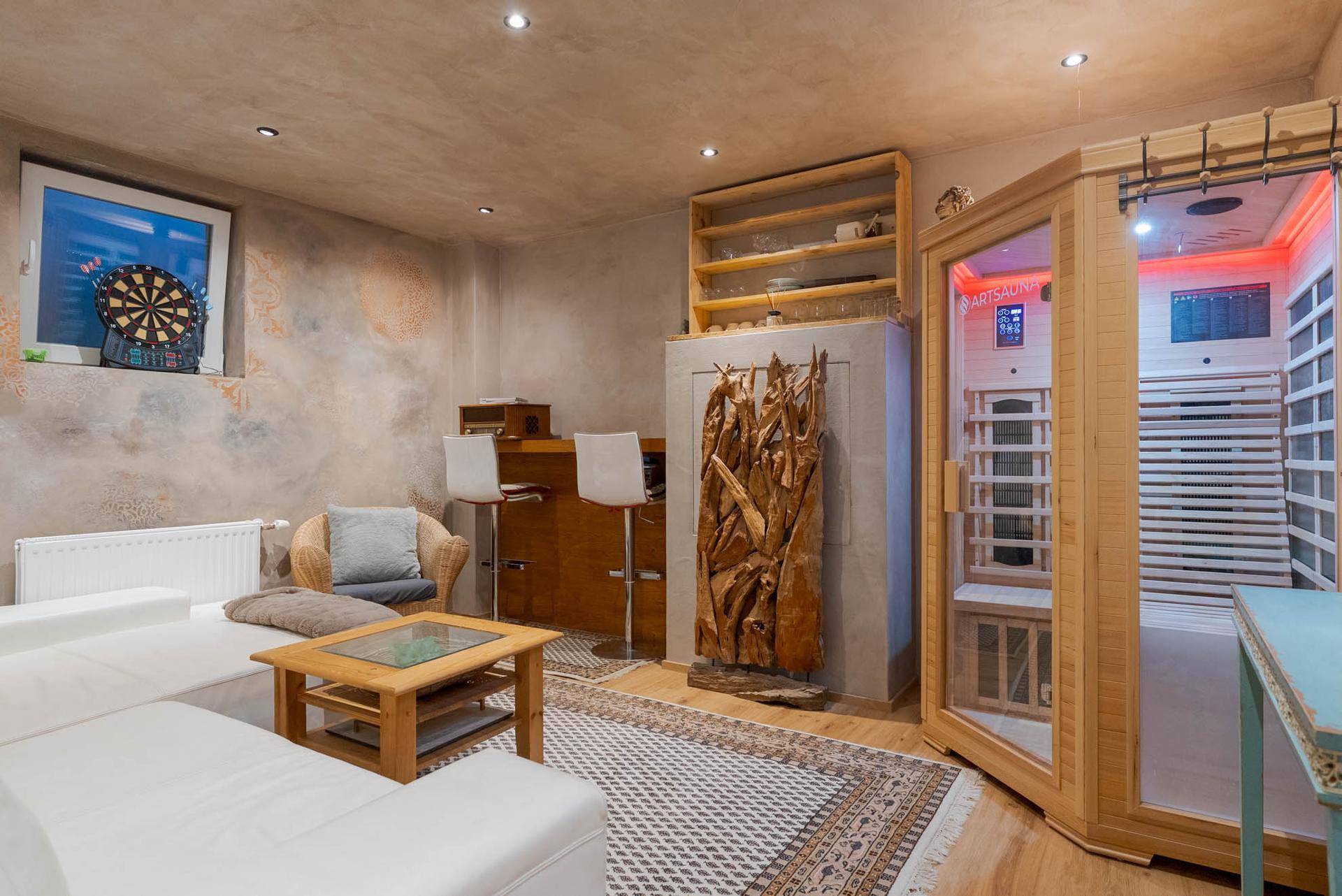 Gemütlicher Wohnbereich mit Sofa, Bar und integrierter Sauna für Wellnessmomente.