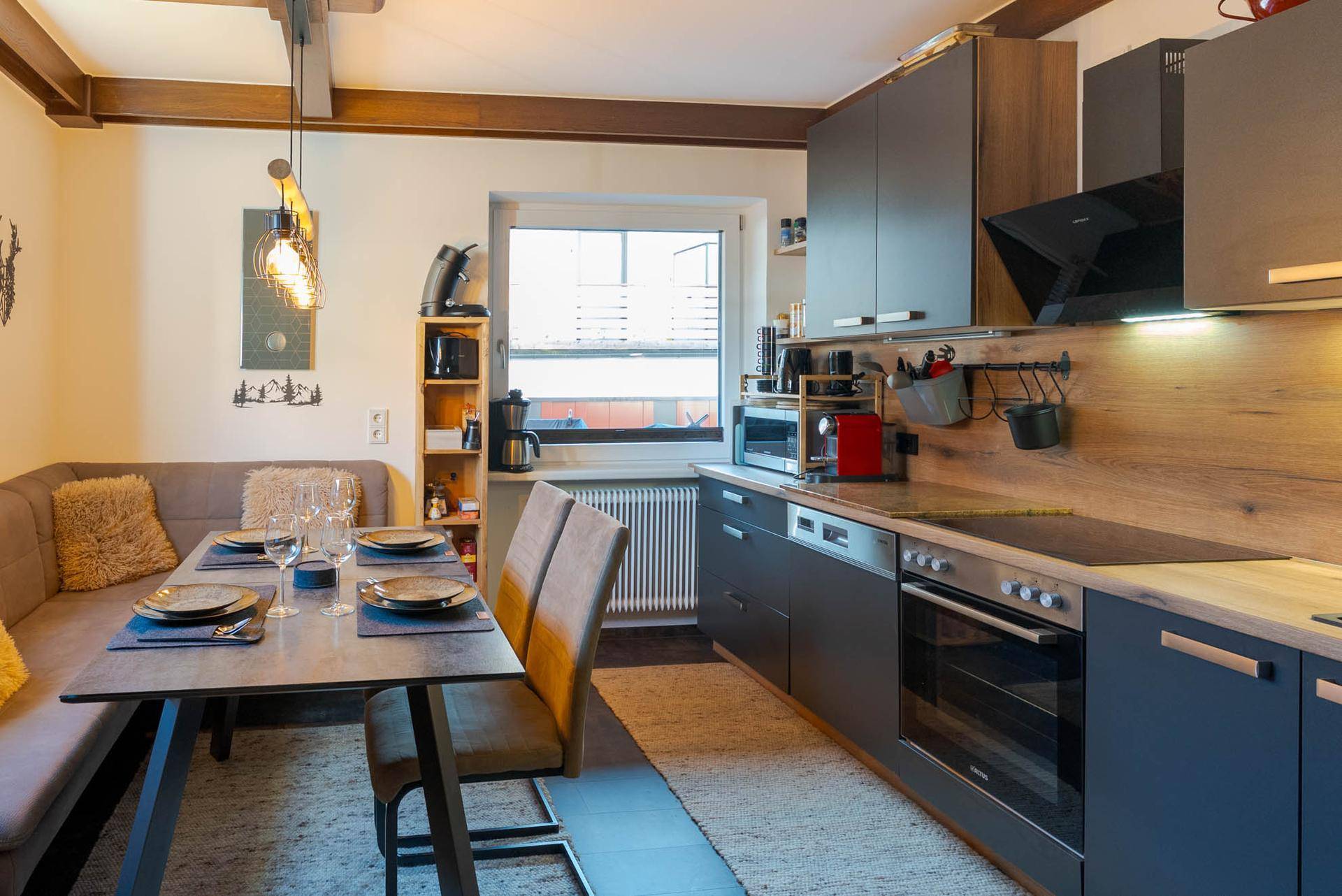 Moderne Wohnküche mit dunklen Schränken, Essbereich und Fenster mit Blick nach draußen.